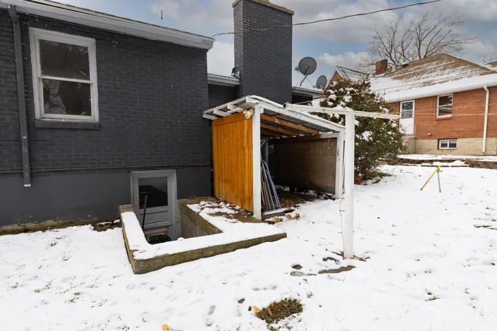 View of snow covered exterior featuring brick siding and a chimney