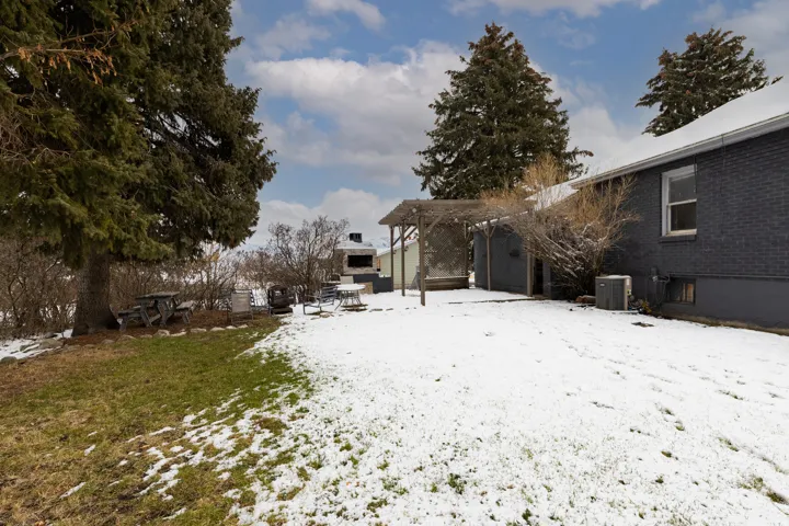 Yard layered in snow with a pergola and a patio area