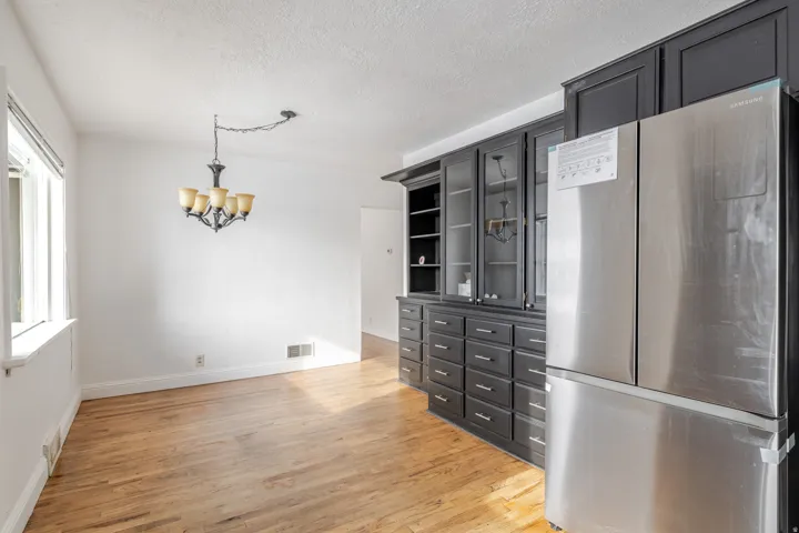 Kitchen with freestanding refrigerator, light wood-style floors, a chandelier, a textured ceiling, and open shelves