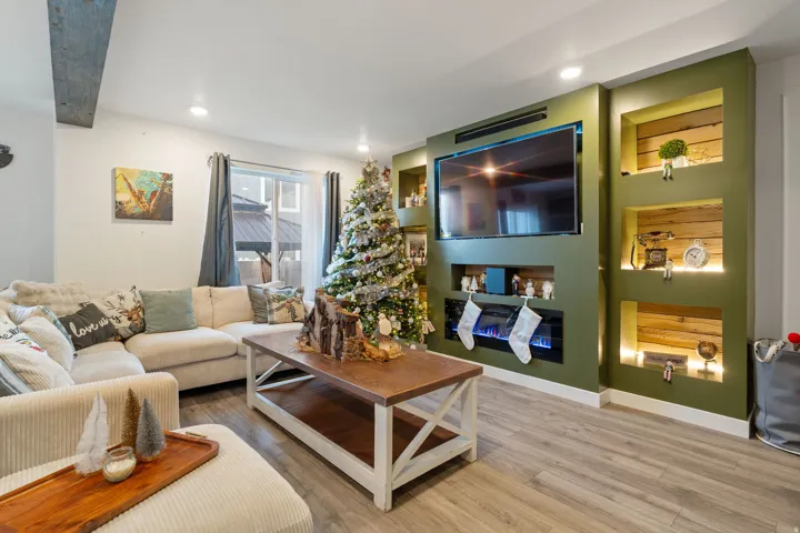 Living room with wood finished floors, built in shelves, and recessed lighting