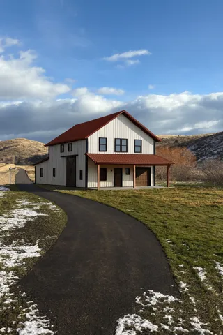 Modern inspired farmhouse featuring a porch, asphalt driveway, an outdoor structure, a mountain view, and a metal roof