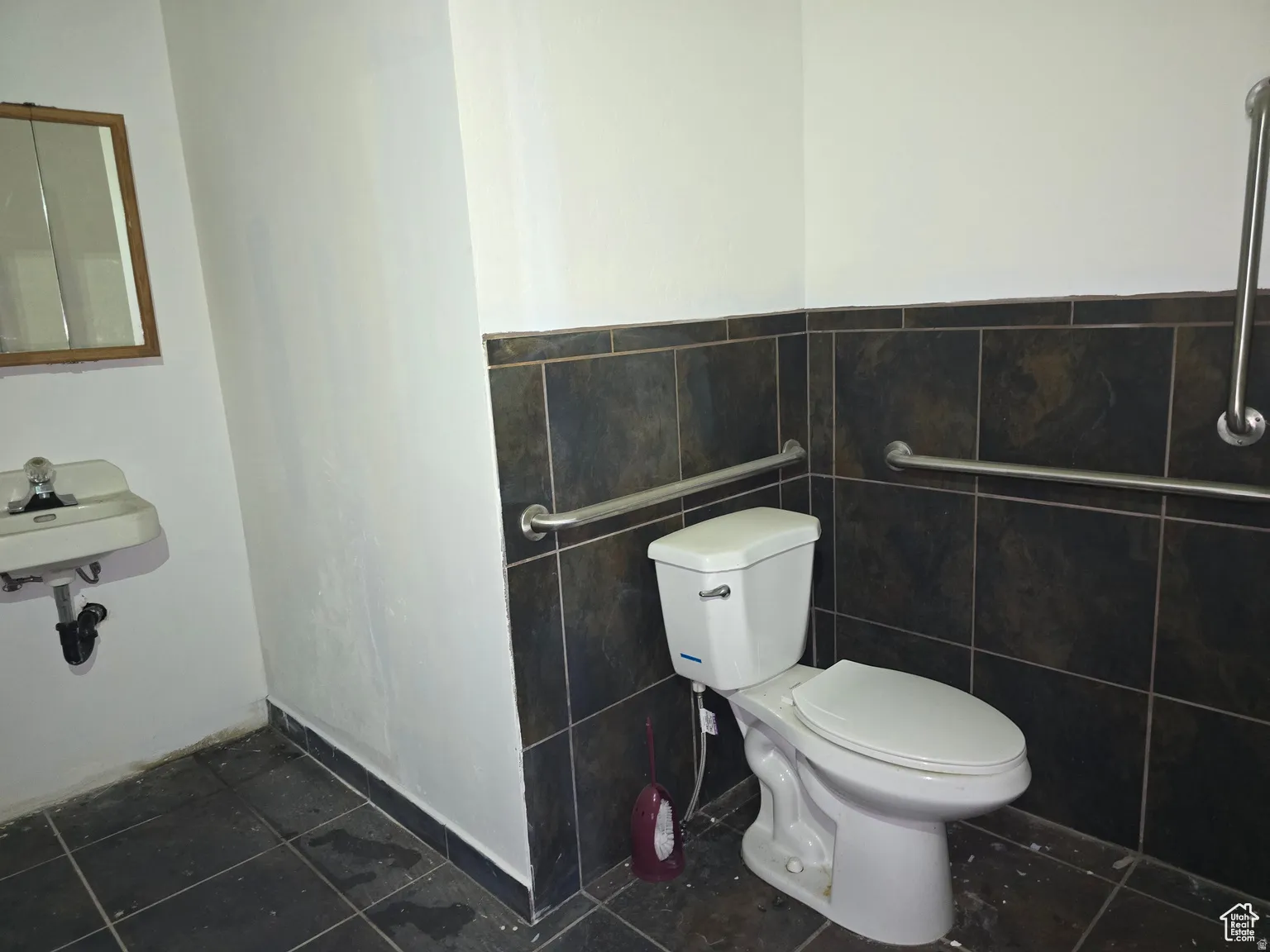 Bathroom featuring dark tile patterned flooring, tile walls, and a wainscoted wall