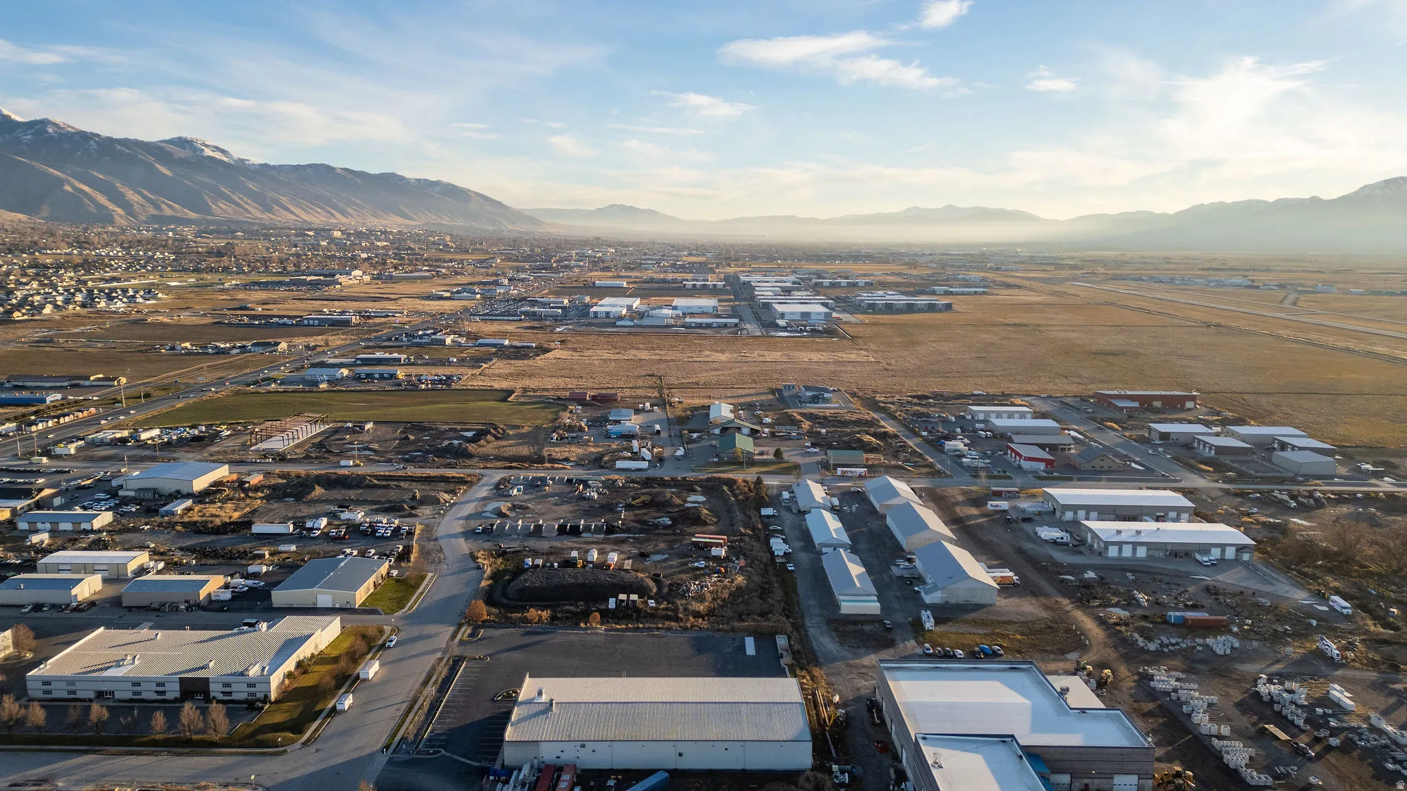 Aerial view of property and surrounding area with industrial structures and a mountain backdrop