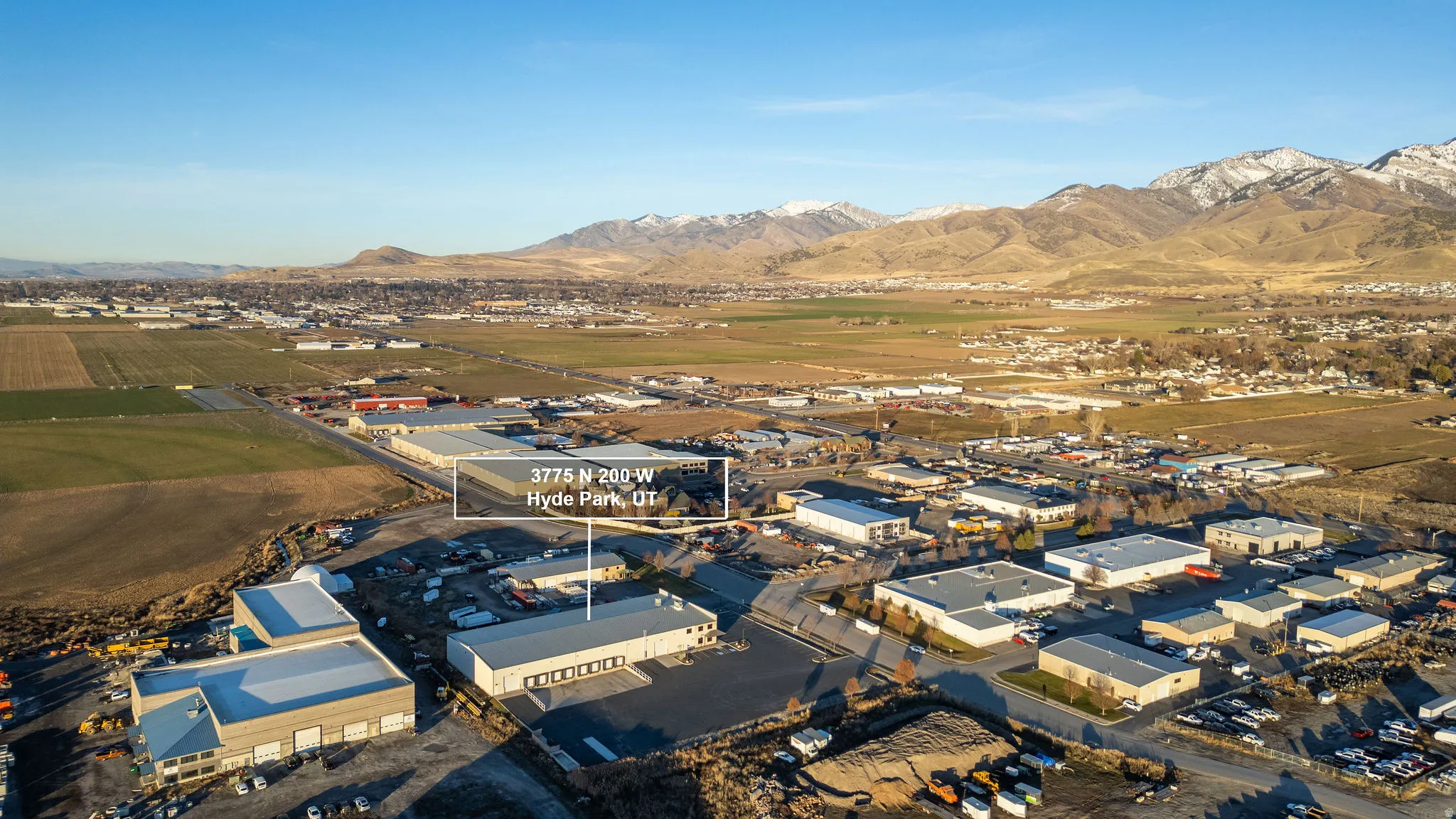 Aerial view of property and surrounding area with an industrial area and a mountainous background