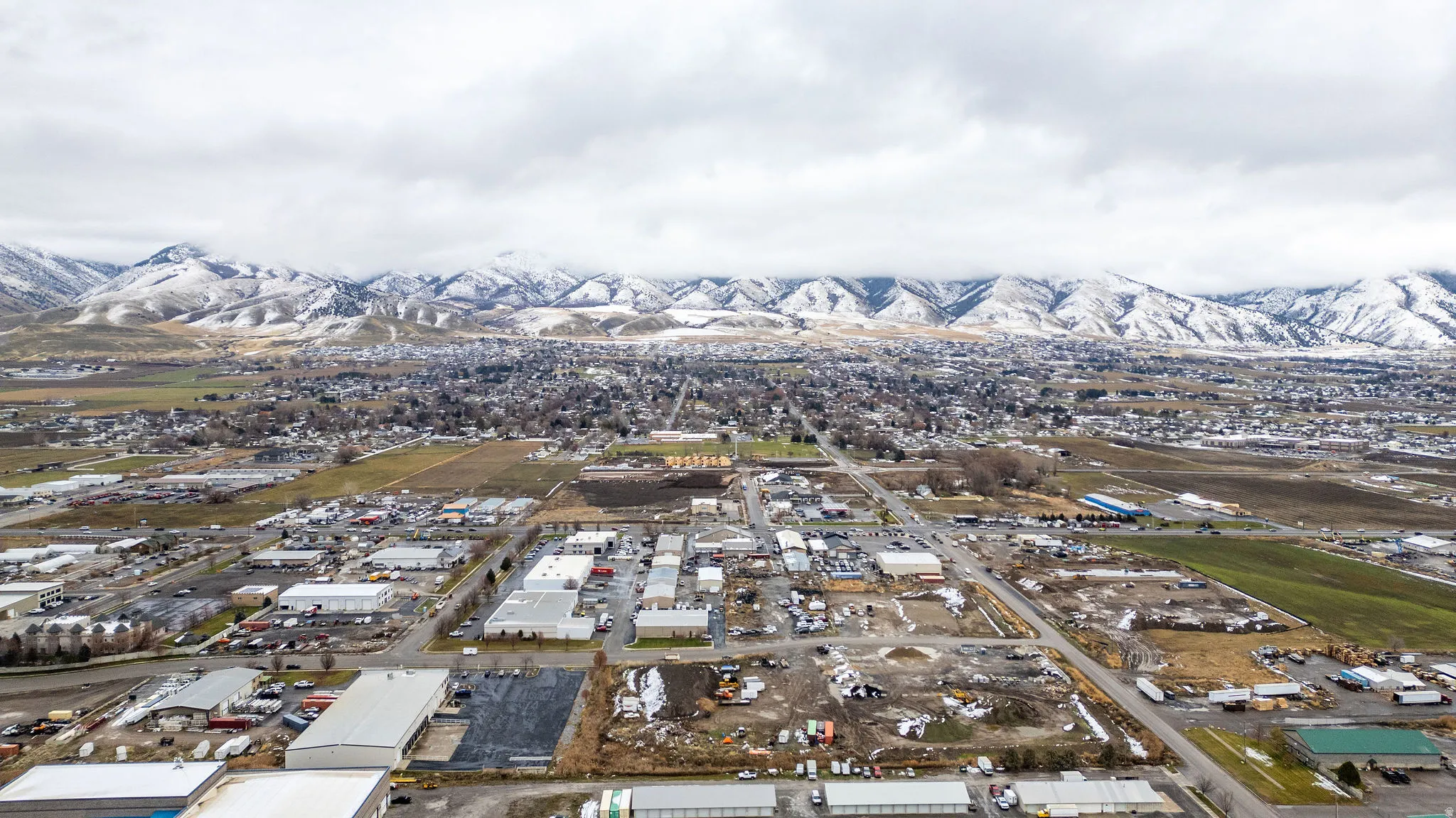 Aerial view of property and surrounding area featuring an industrial area and mountains