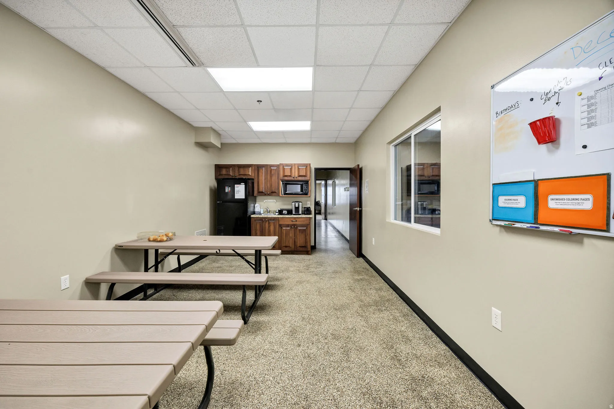Kitchen with a drop ceiling, brown cabinetry, black appliances, and light countertops