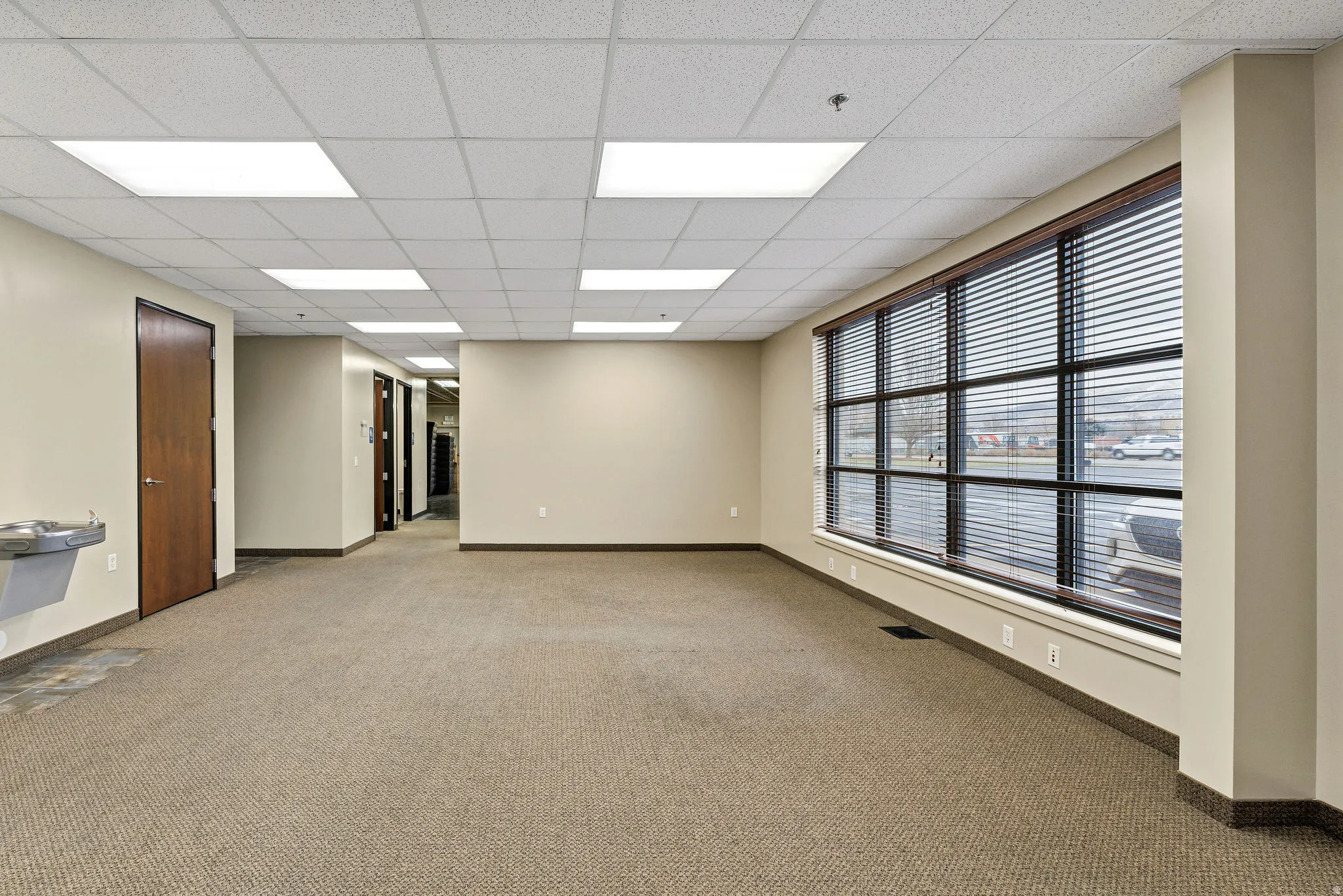 Empty room with a drop ceiling and light carpet