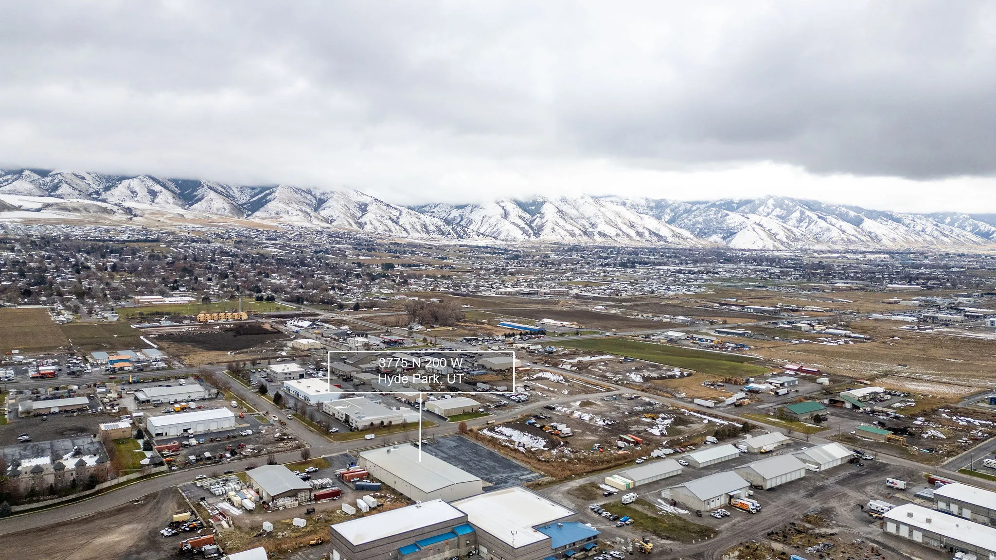 Aerial view of property and surrounding area featuring industrial structures and a mountainous background
