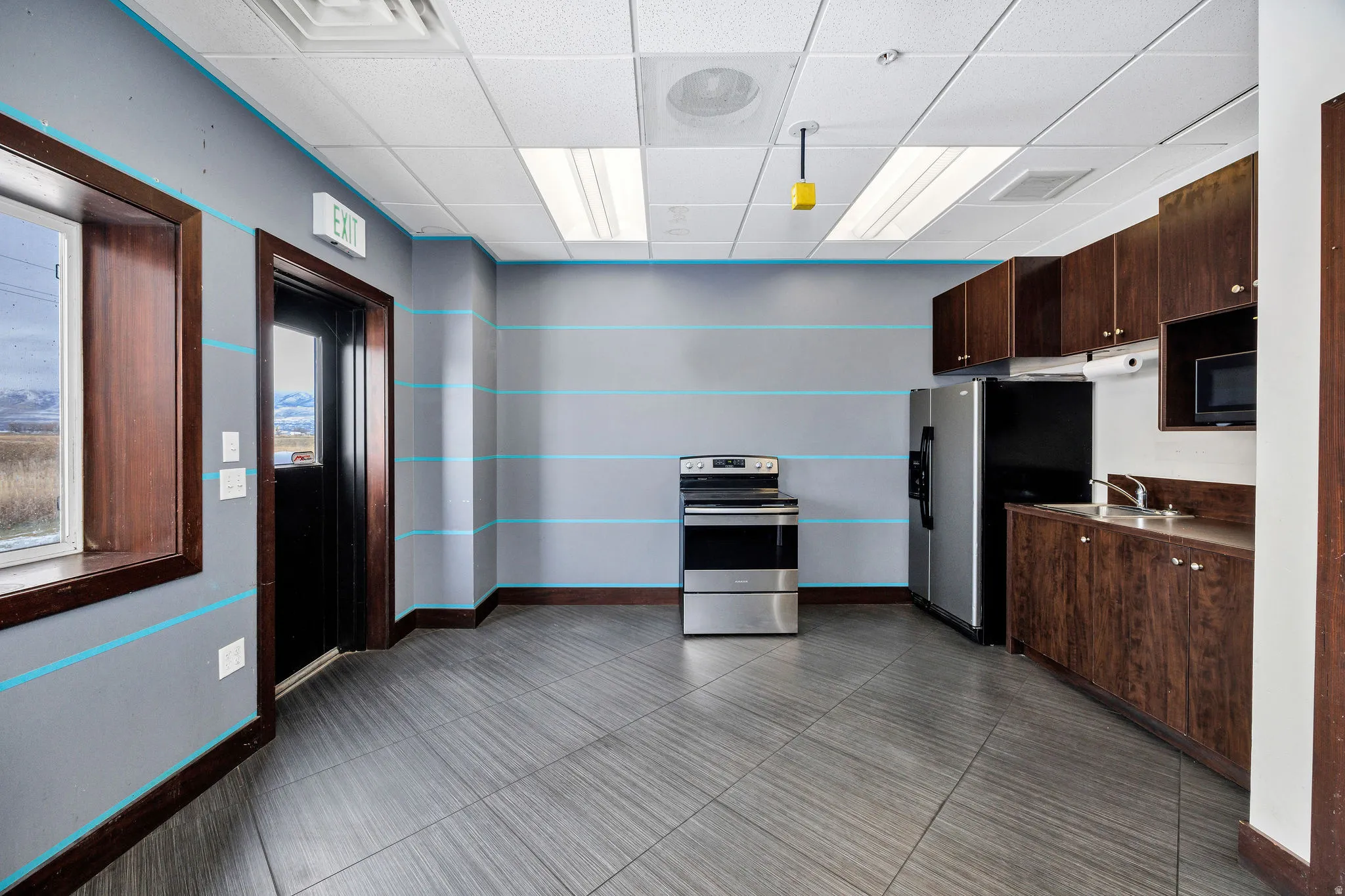 Kitchen with dark brown cabinets, a paneled ceiling, appliances with stainless steel finishes, and dark countertops