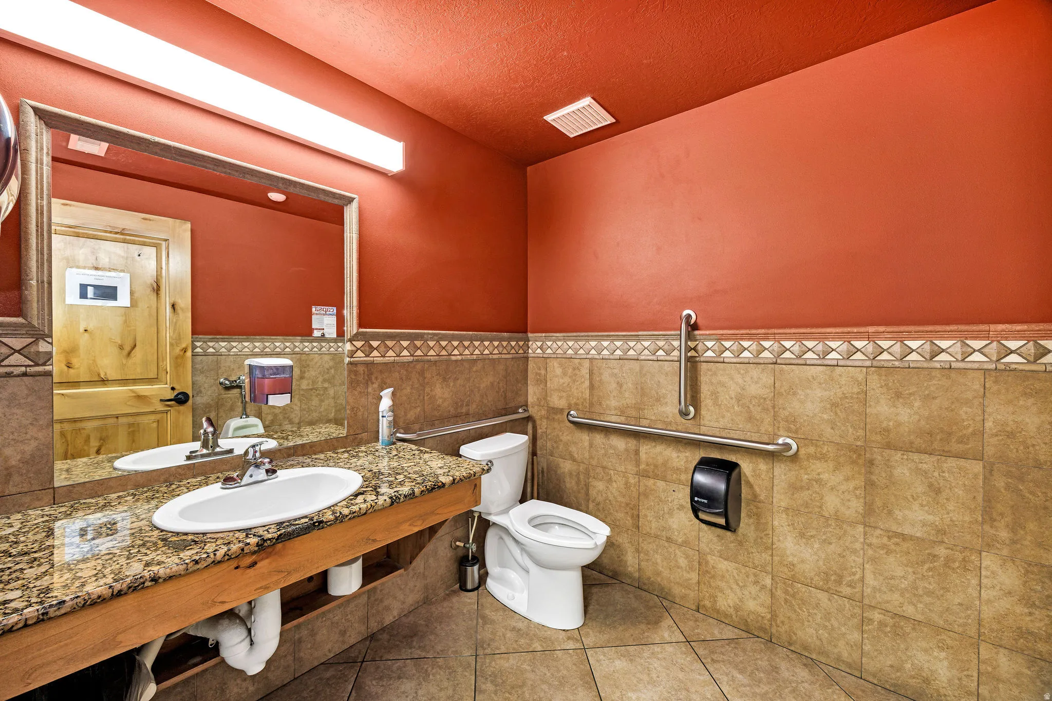 Bathroom featuring a wainscoted wall, tile patterned floors, tile walls, a textured ceiling, and vanity
