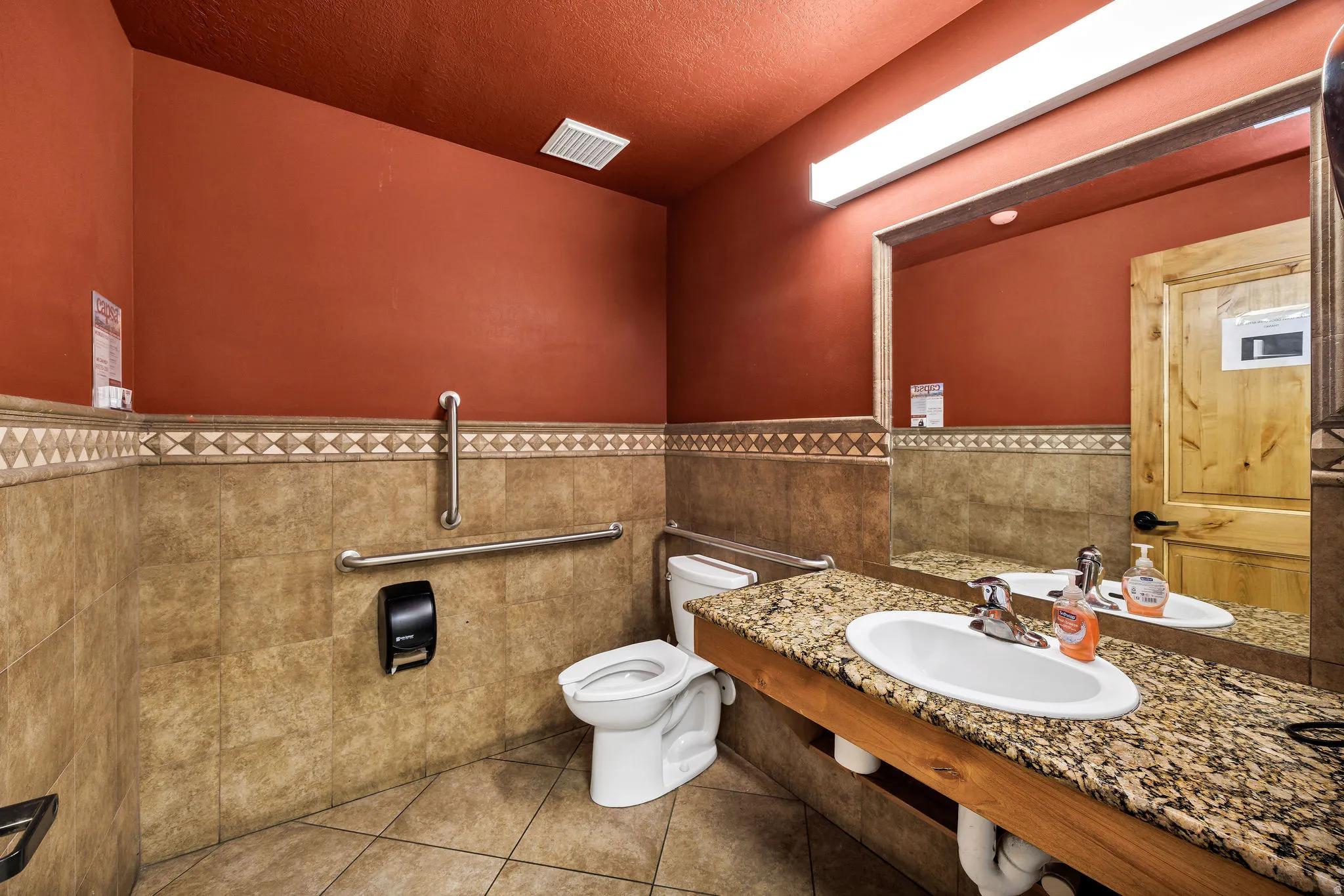 Bathroom with light tile patterned floors, a wainscoted wall, tile walls, vanity, and a textured ceiling