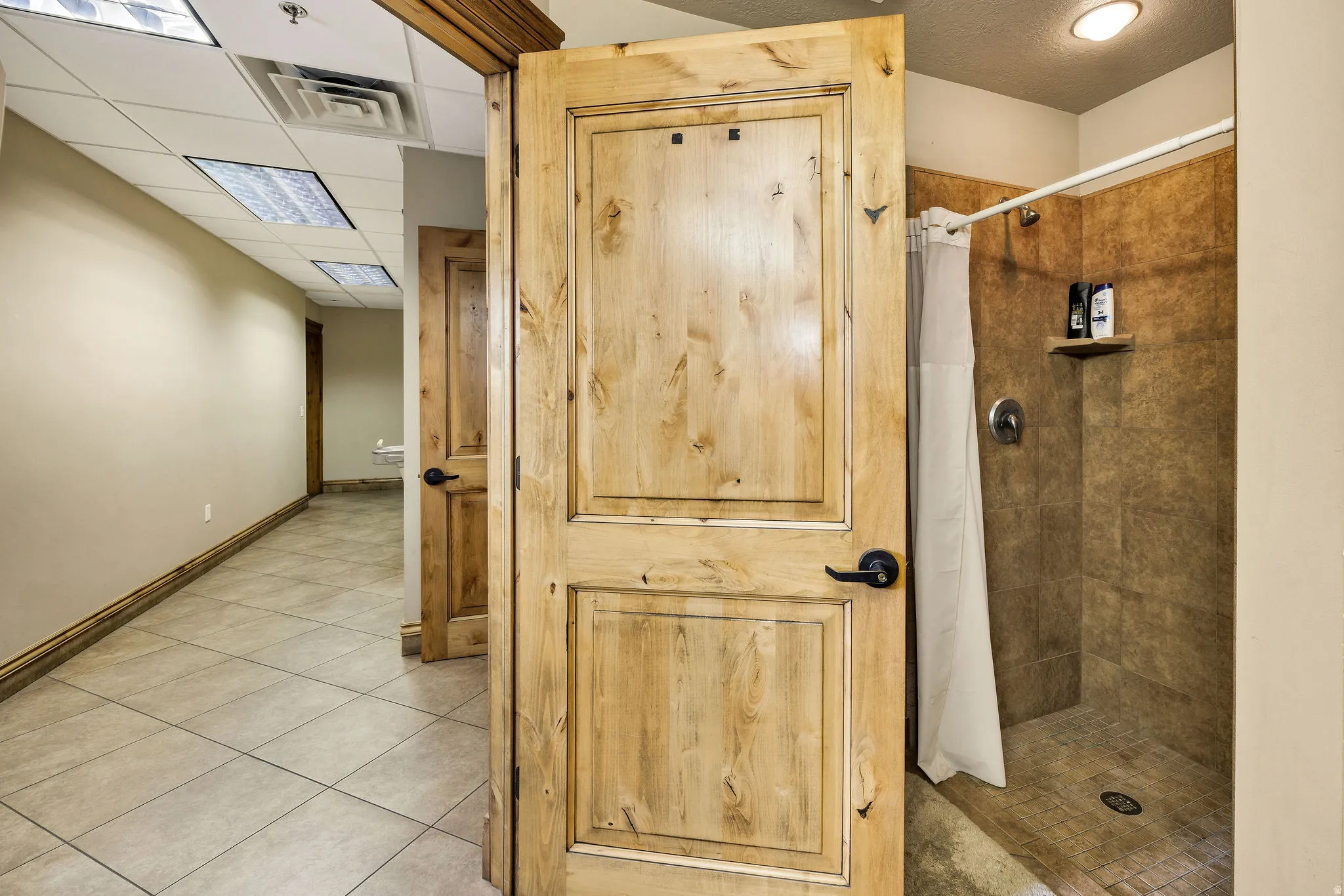 Full bath featuring a tile shower and tile patterned flooring