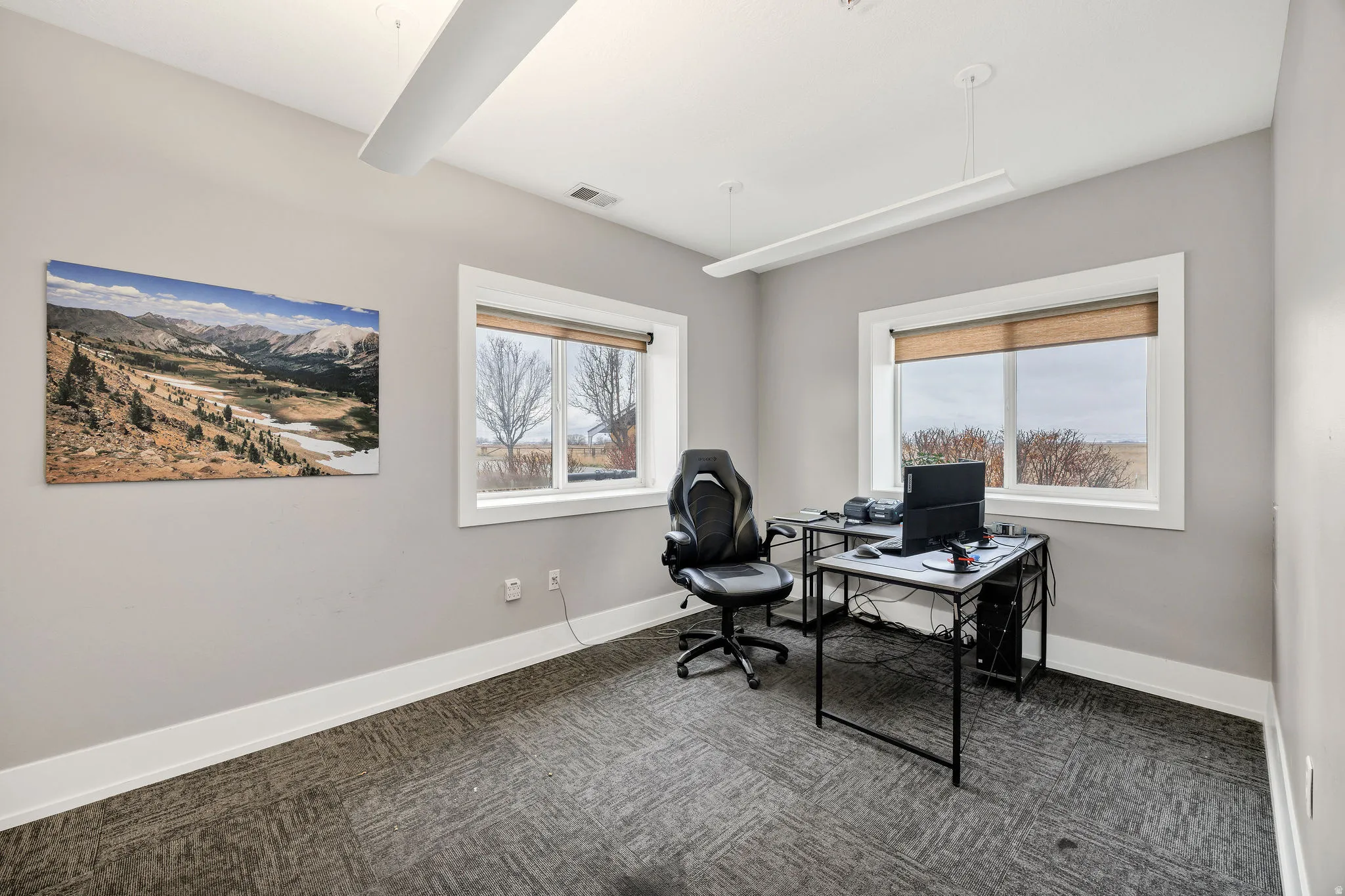 Office area with baseboards and dark carpet