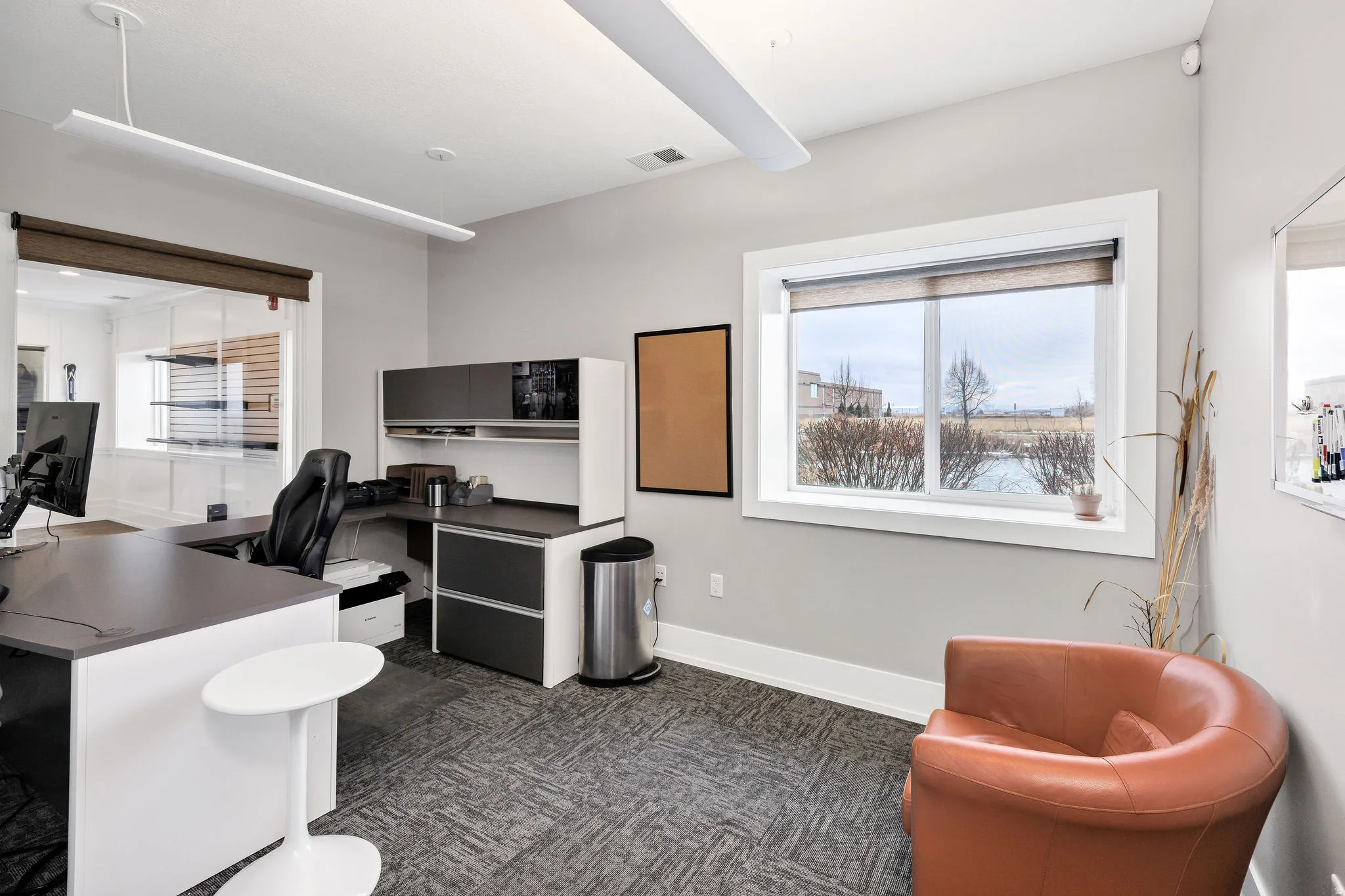 Home office with plenty of natural light and dark carpet
