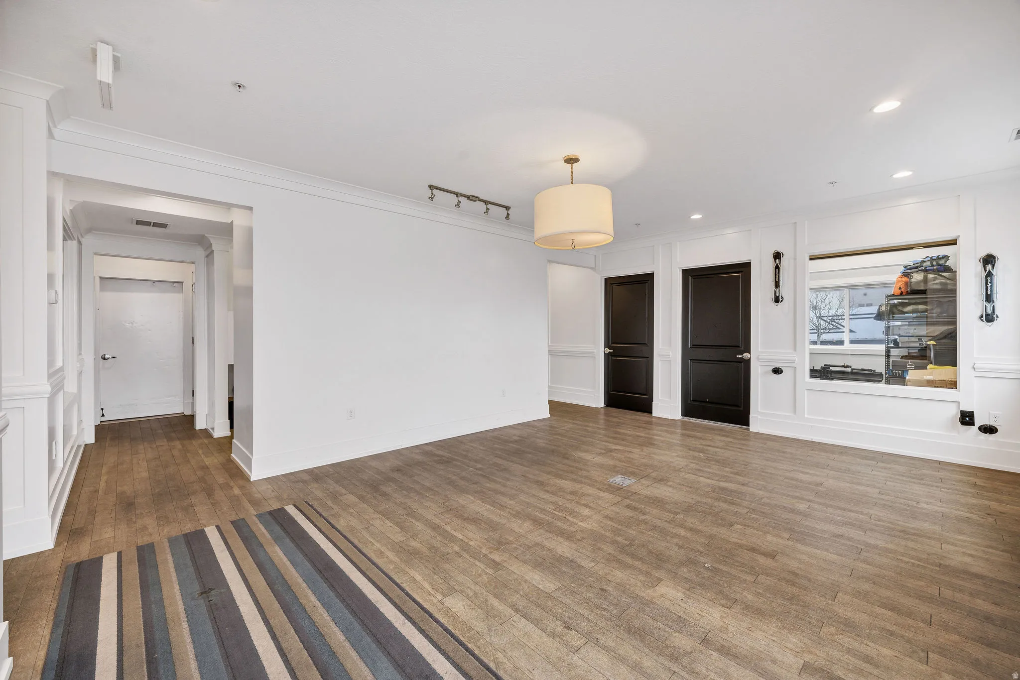 Unfurnished living room featuring dark wood-style flooring, ornamental molding, track lighting, and recessed lighting