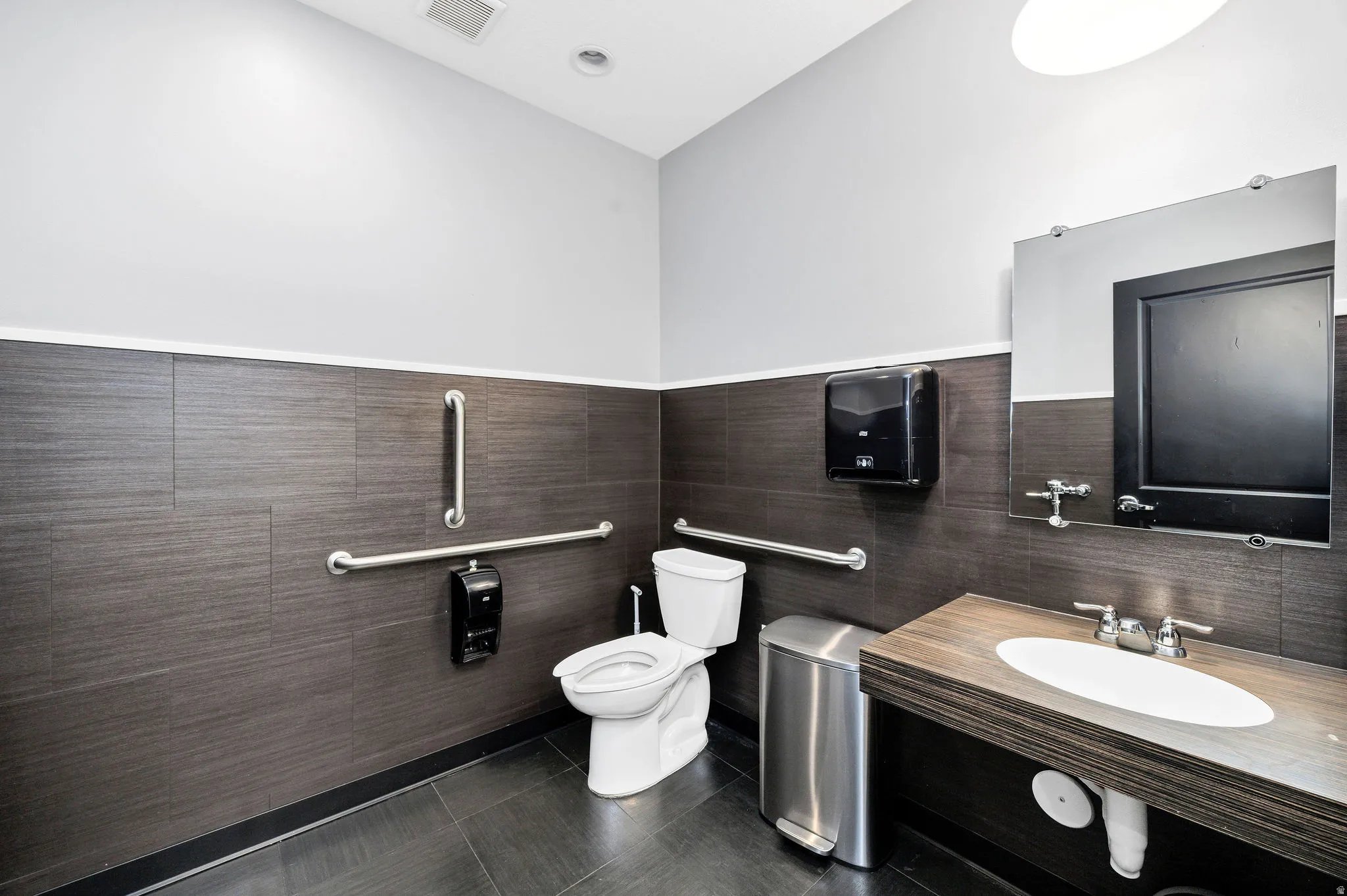 Half bathroom featuring dark tile patterned flooring, vanity, and tile walls