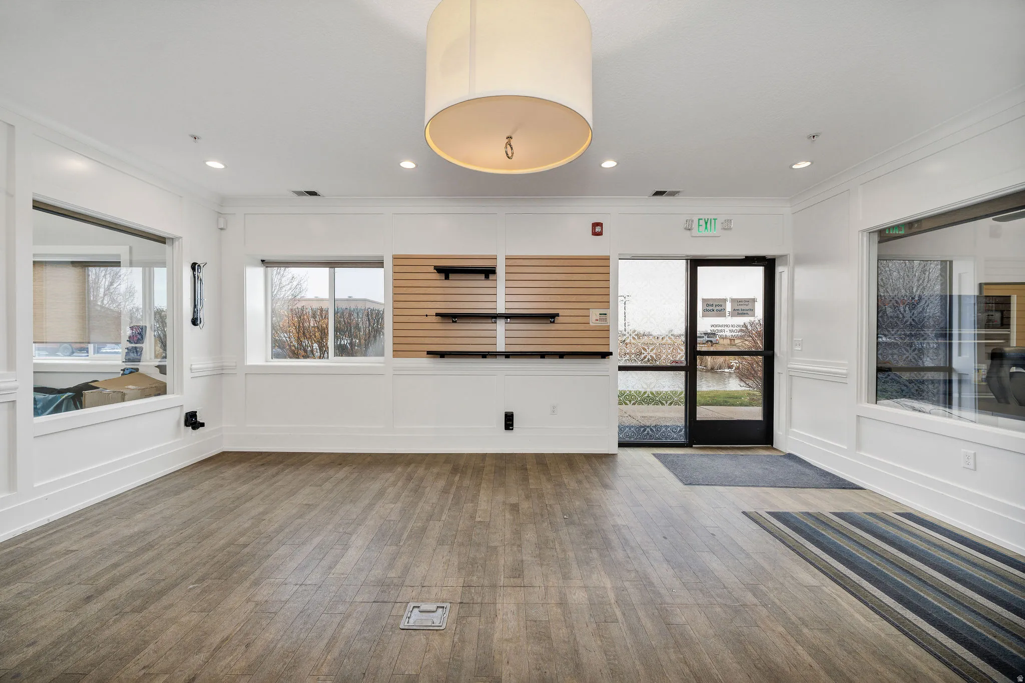 Unfurnished living room featuring a decorative wall, crown molding, wood finished floors, plenty of natural light, and recessed lighting