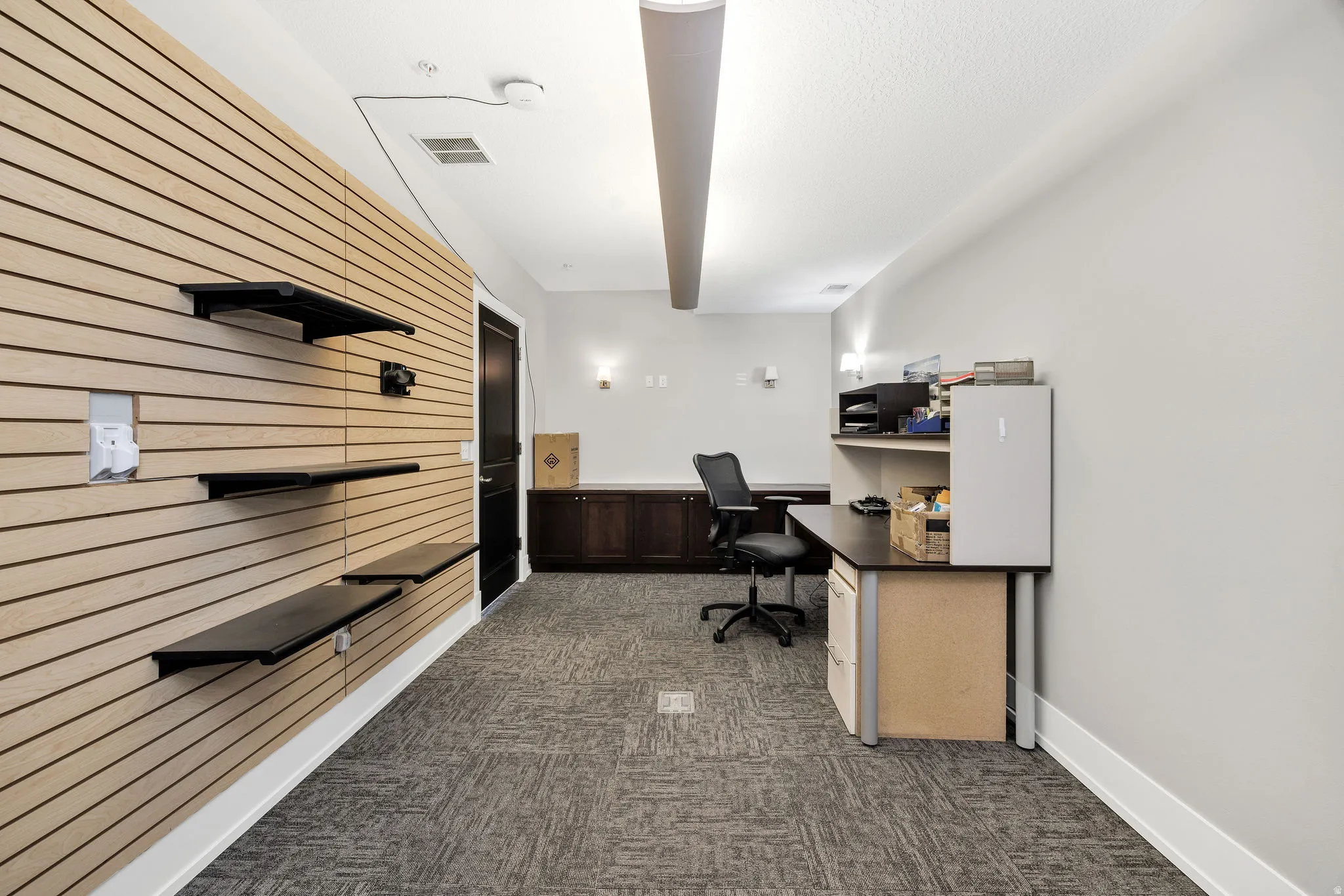 Office area featuring dark carpet and wood walls