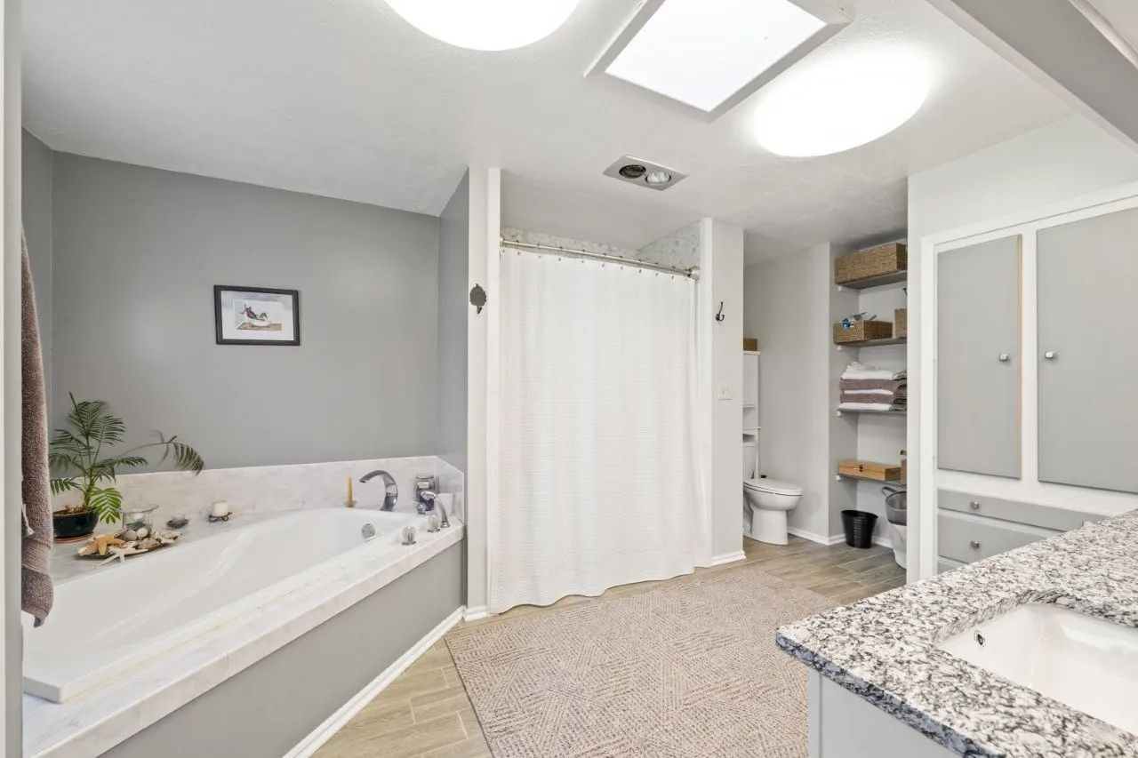 Full bathroom with double vanity, a shower with curtain, wood tiled floors, and a garden tub