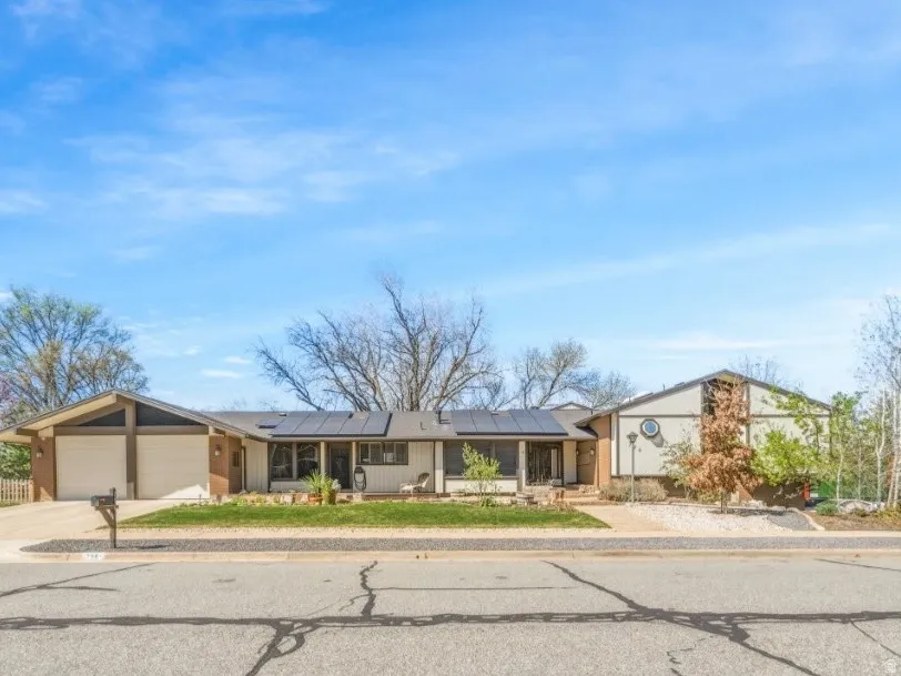 Mid-century home featuring solar panels, a garage, and concrete driveway