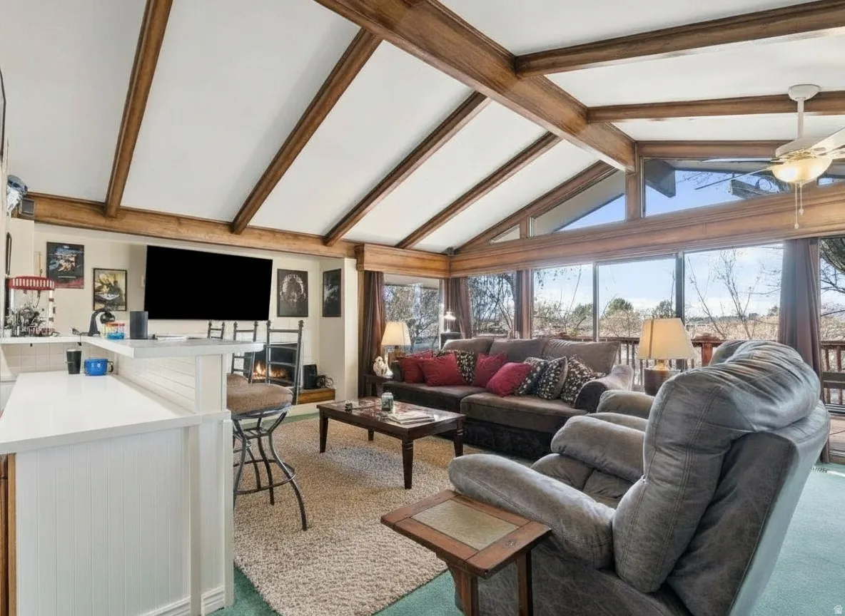 Living area featuring a vaulted ceiling with exposed wood beams, a built-in fireplace, and expansive windows