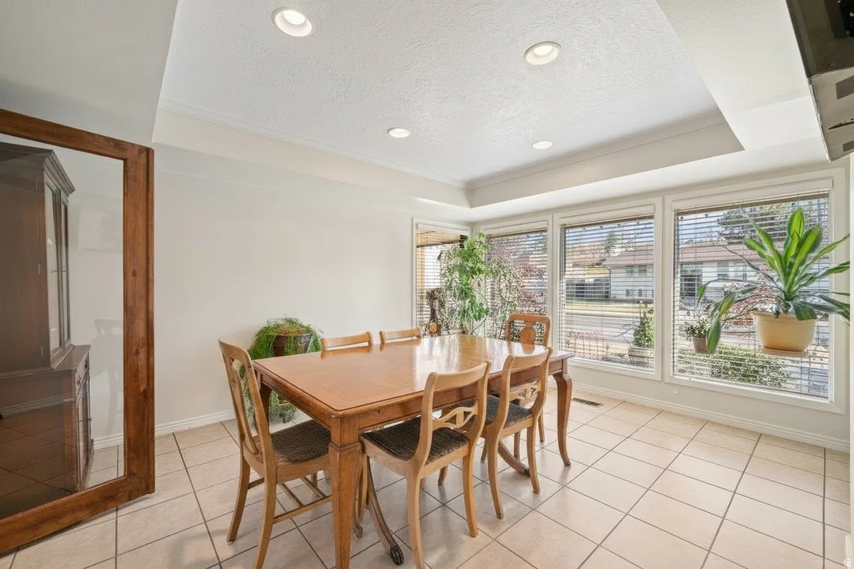Dining area featuring a tray ceiling with recessed lighting, large windows, and neutral tile flooring