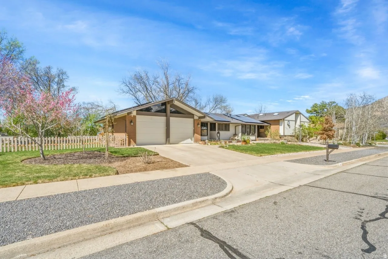 View of front of property featuring an attached garage, driveway, and roof mounted solar panels
