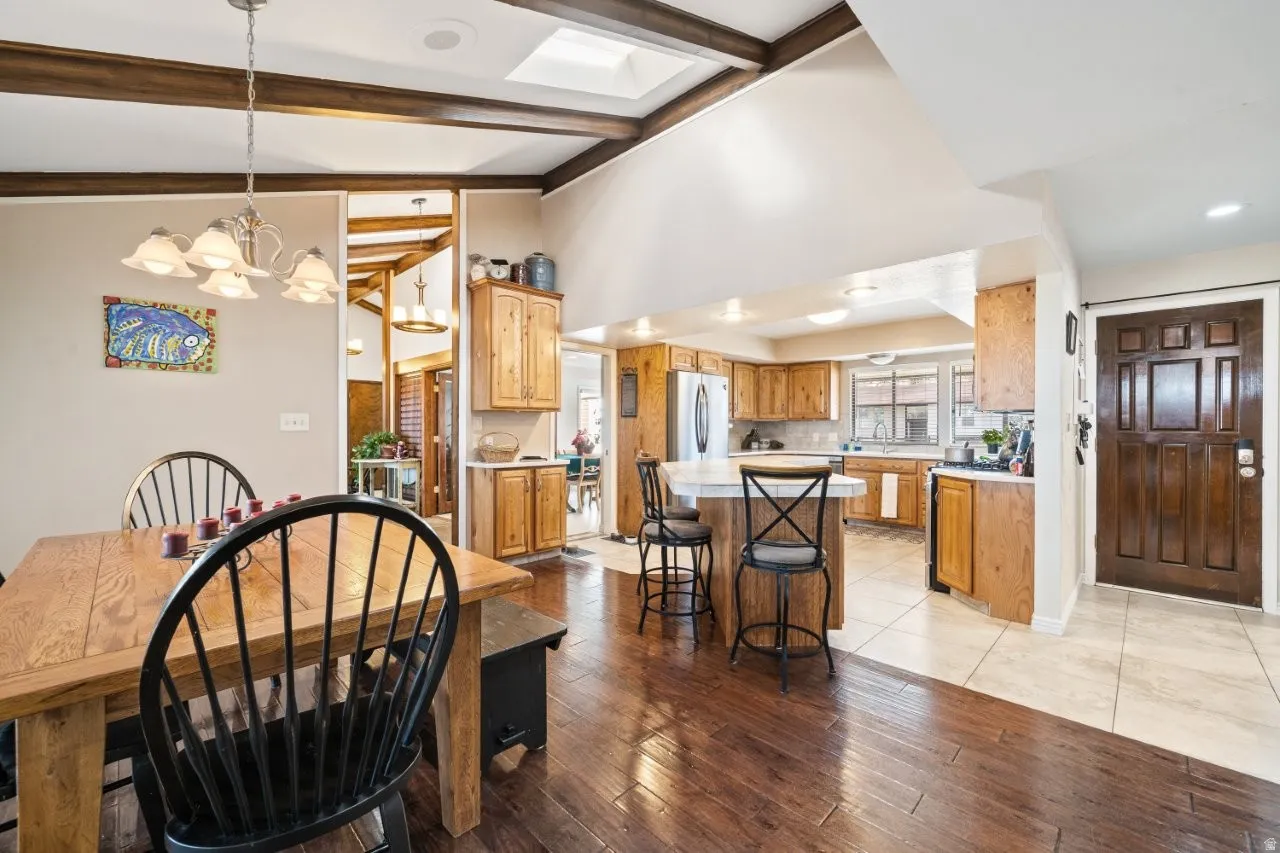 Dining space featuring light wood-style floors, a skylight, a chandelier, and high vaulted ceiling