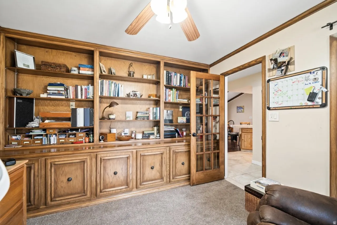 Office area with crown molding, a ceiling fan, and light colored carpet