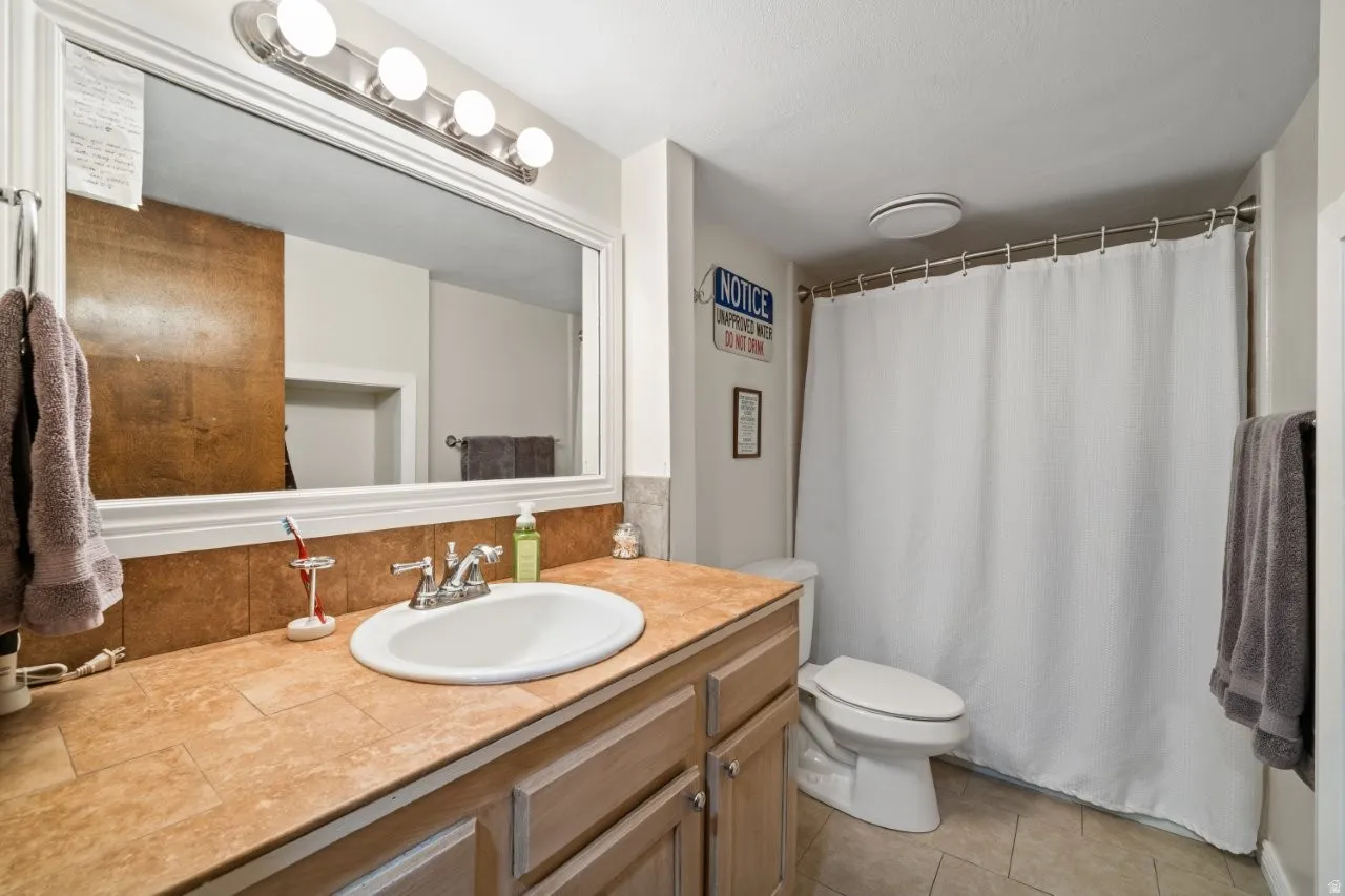 Full bathroom with vanity, curtained shower, light tile patterned floors, and backsplash