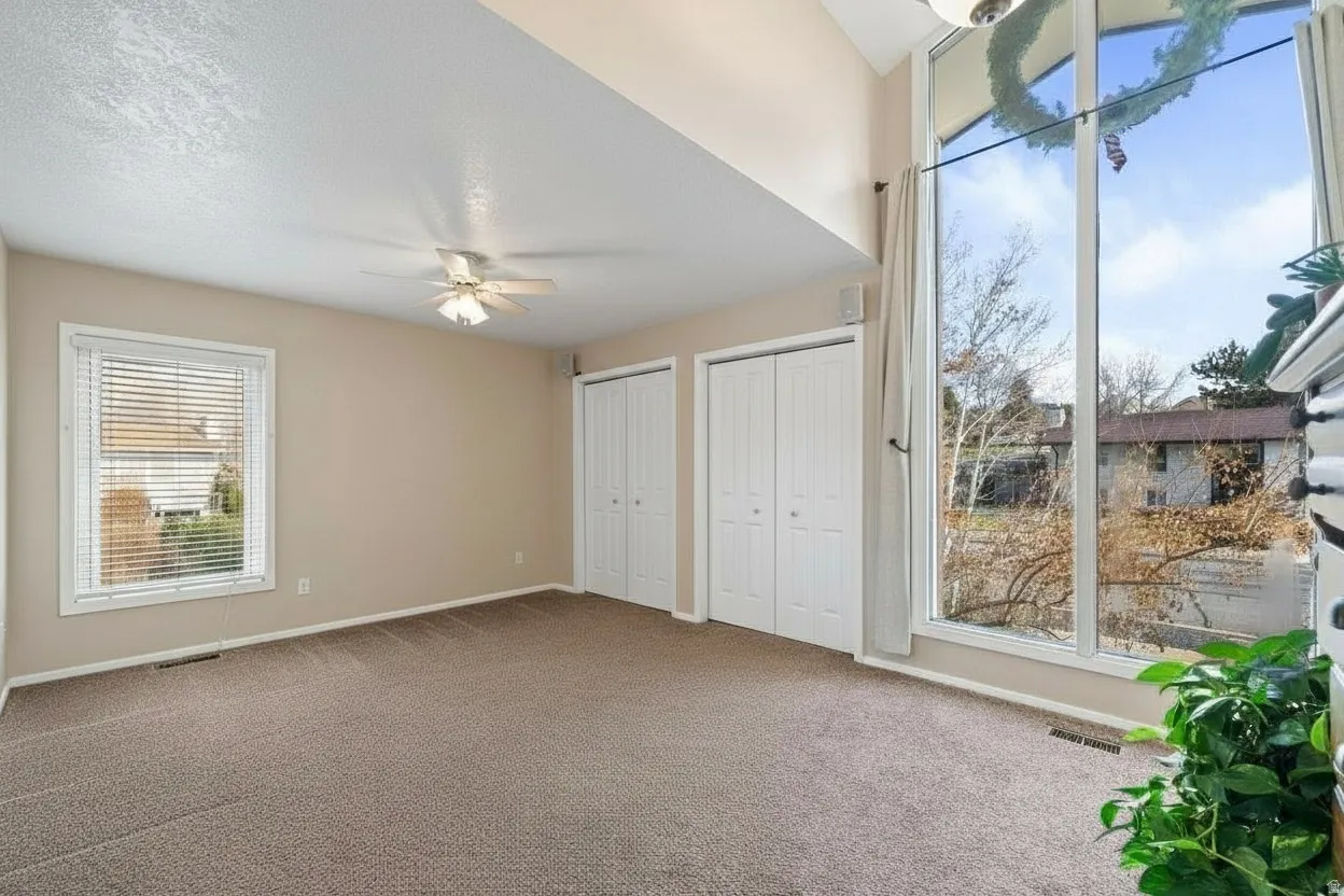 Carpeted room featuring a vaulted ceiling and an expansive multi-pane window