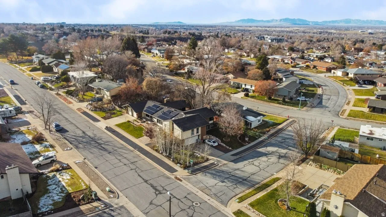 Aerial view of property and surrounding area with nearby suburban area and a mountain backdrop
