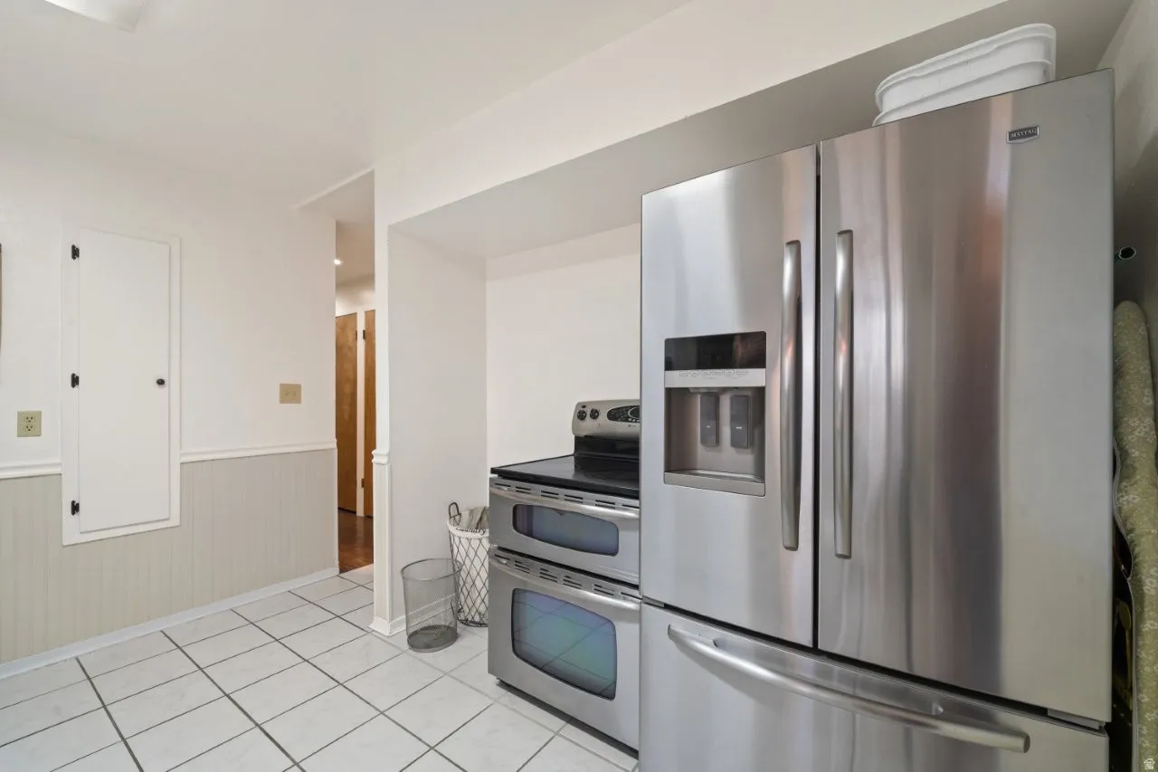 Kitchen featuring stainless steel appliances, wainscoting, and light tile patterned floors