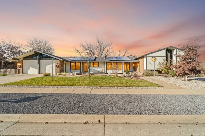 Single-story residence featuring a two-car garage with overhead doors, a paved driveway, and a front lawn