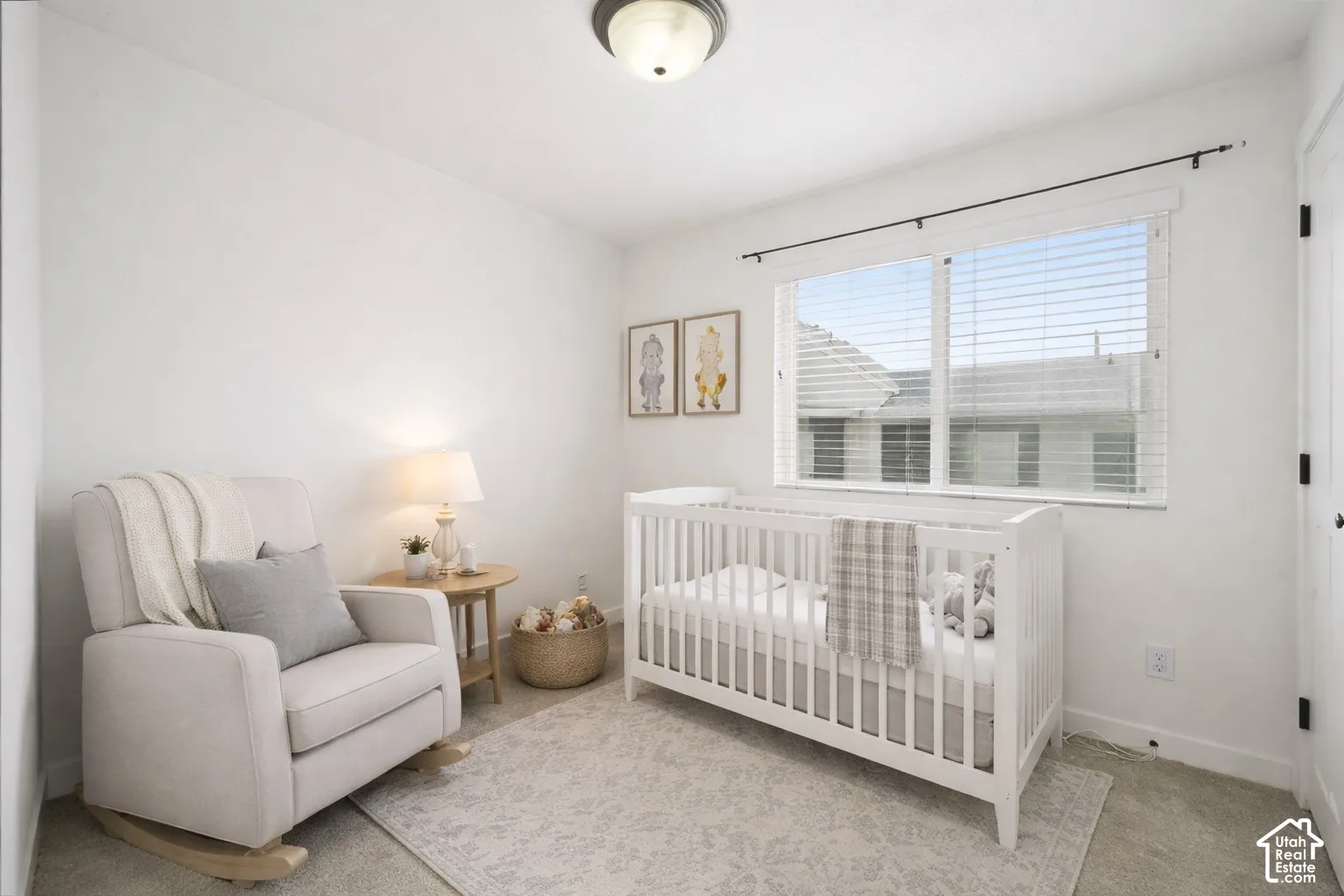 Carpeted bedroom featuring a nursery area and baseboards. Virtually staged.