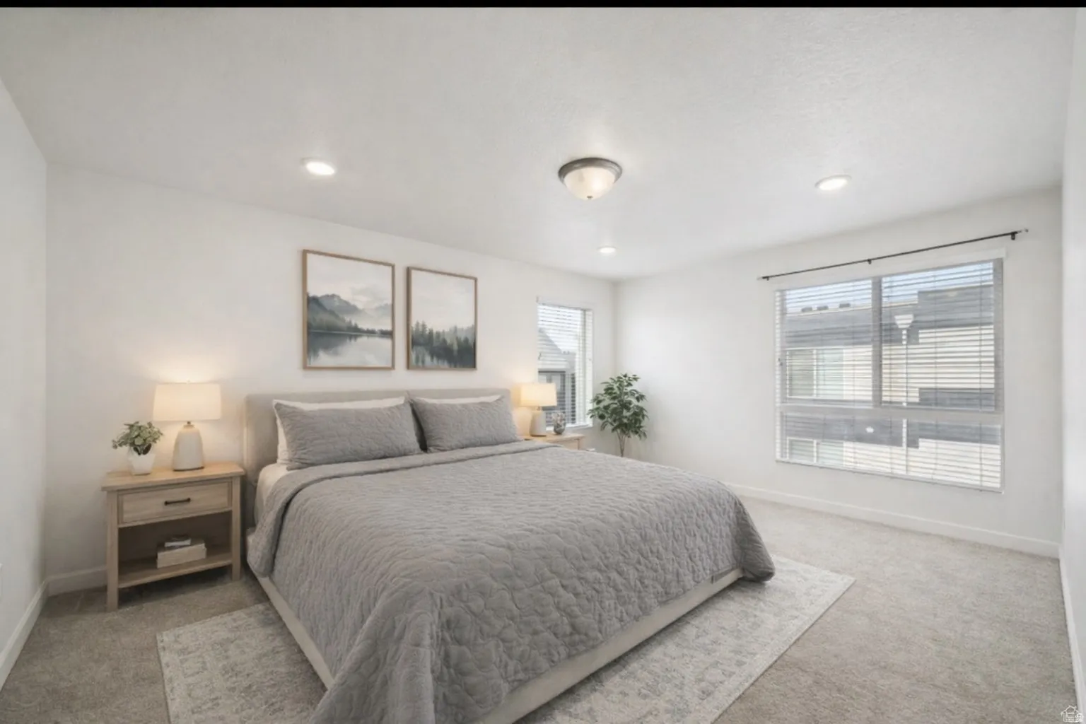 Primary bedroom with two windows, natural light, featuring light colored carpet and recessed lighting.  Virtually staged.