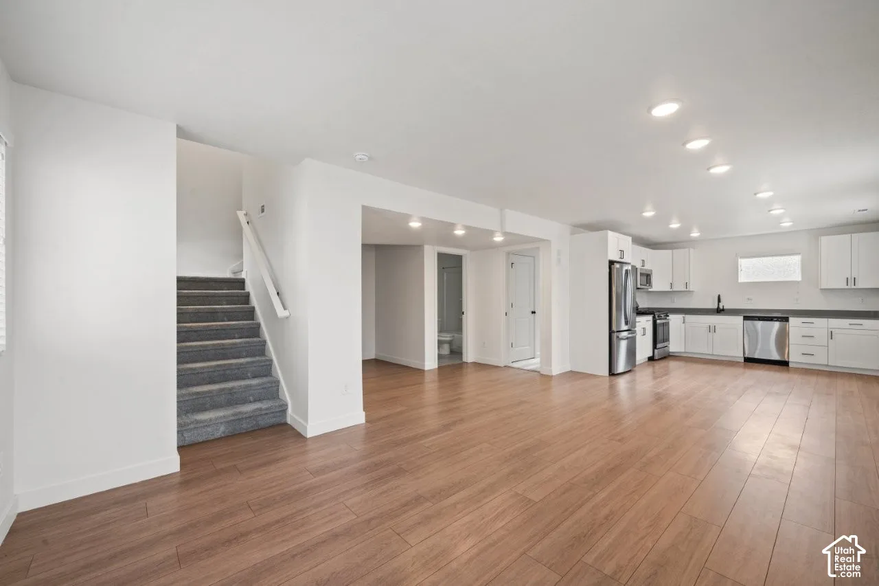 Unfurnished living room with stairway, light wood finished floors, and recessed lighting