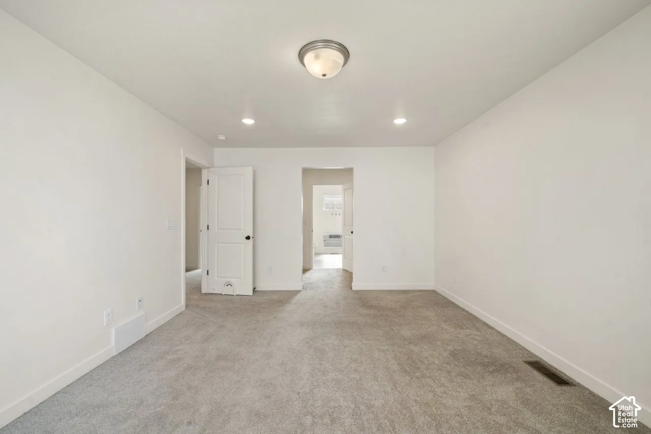 Empty room with light colored carpet and recessed lighting