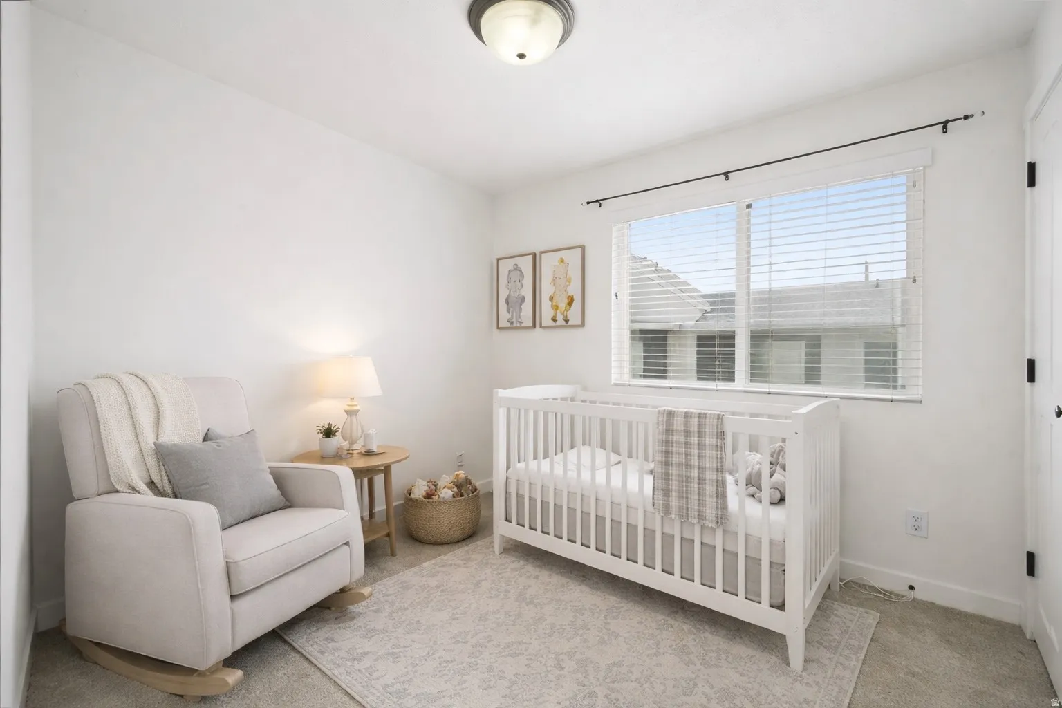 Carpeted bedroom featuring a nursery area and baseboards. Virtually staged.