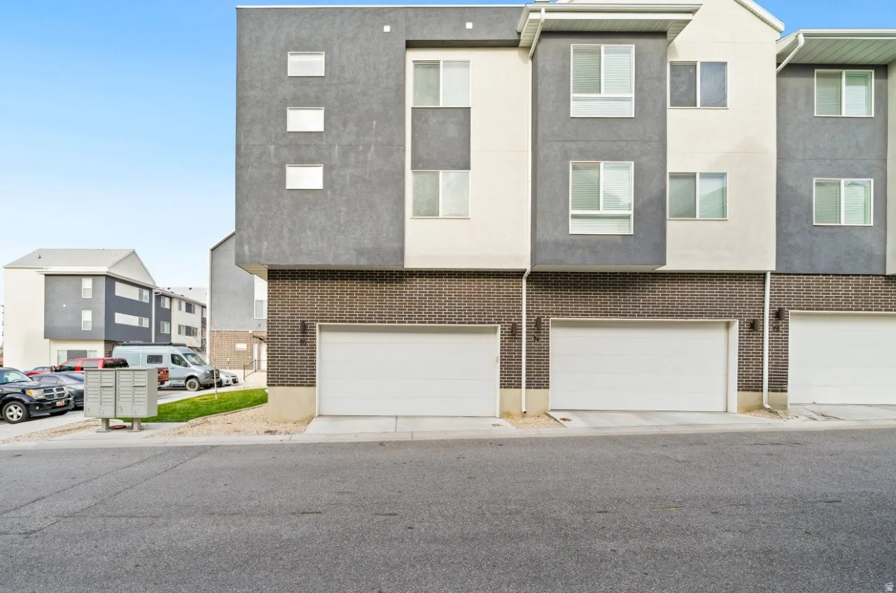 View of back of property featuring stucco siding, a garage, and brick siding