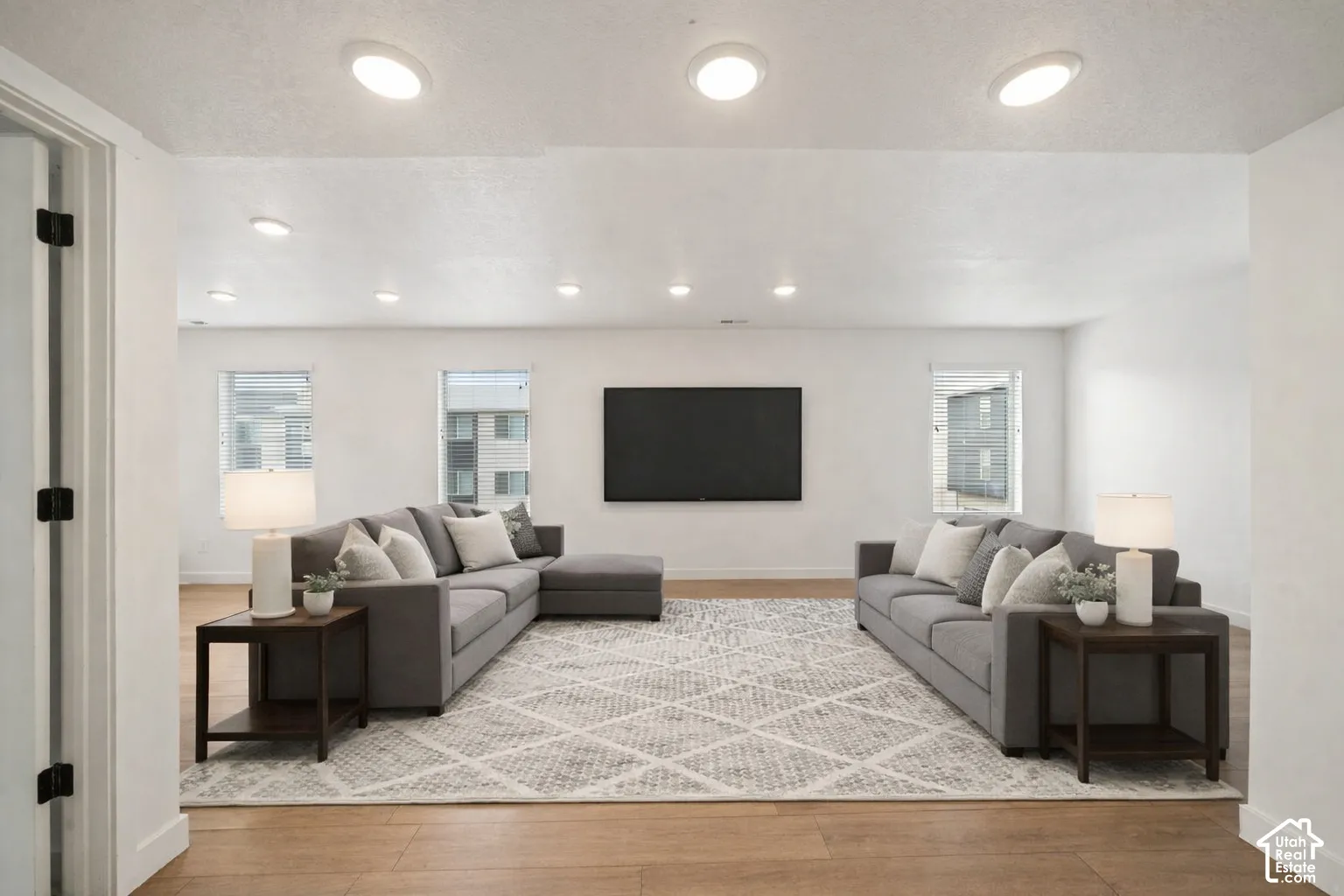 Living room featuring light wood-style flooring and healthy amount of natural light. Virtually staged.