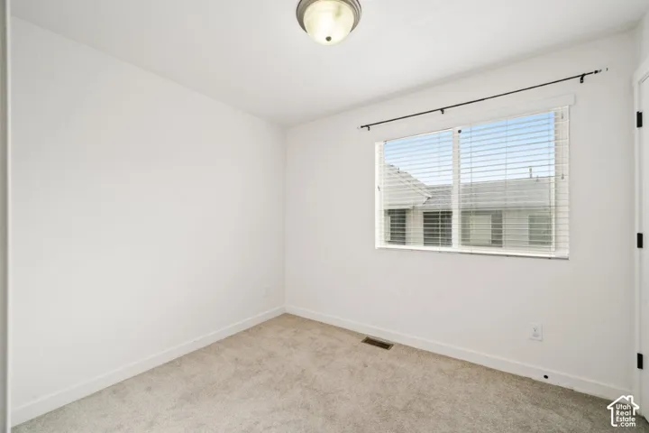 Spare room featuring baseboards and light colored carpet