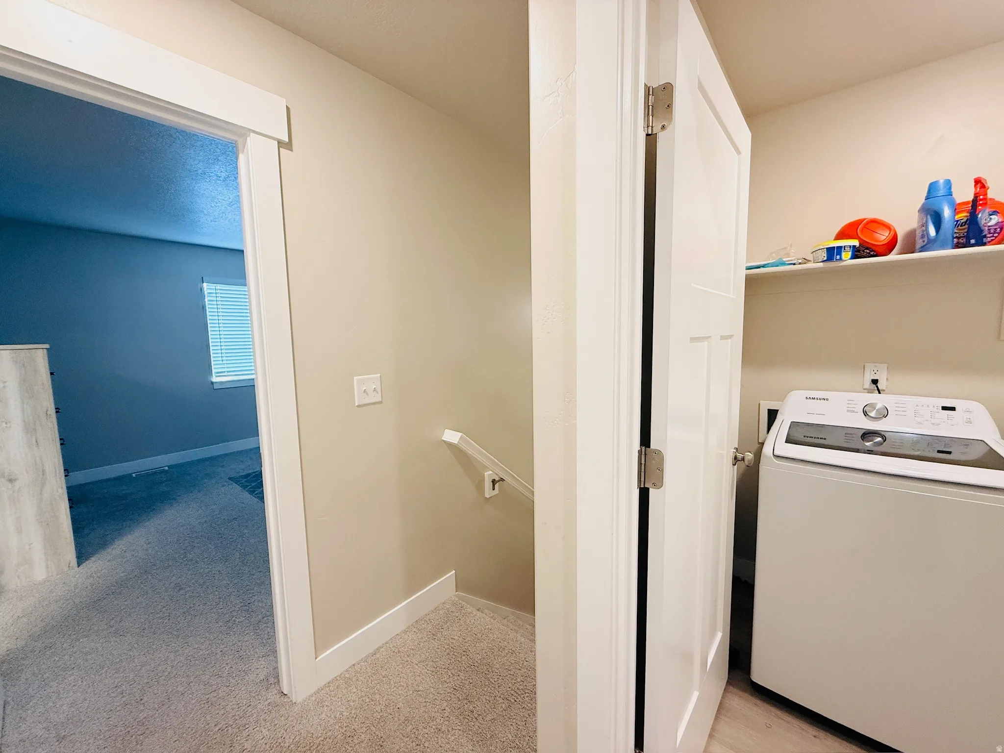 Laundry room featuring washer / clothes dryer, light carpet, and a textured ceiling
