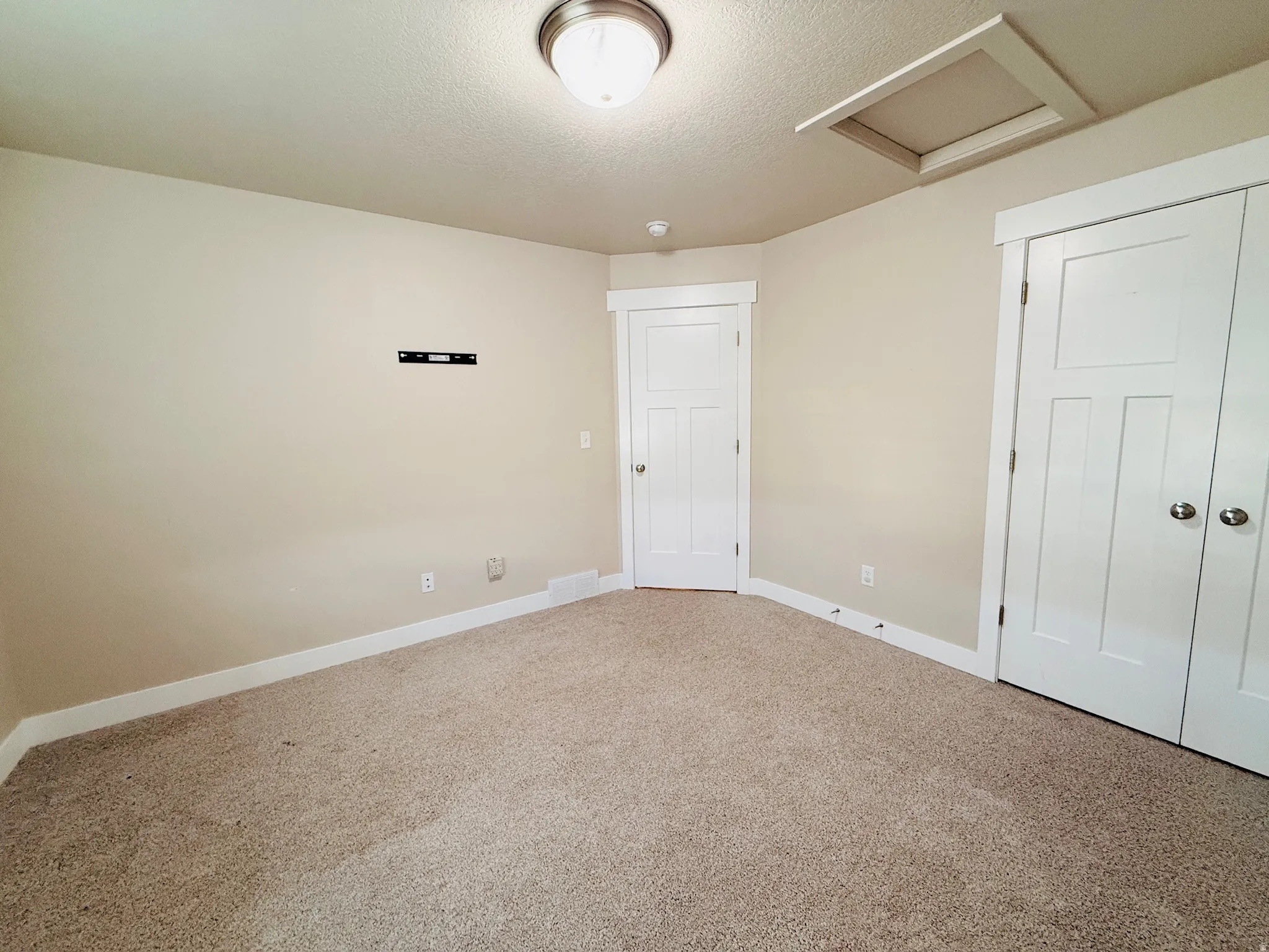 Unfurnished bedroom featuring attic access, carpet, a closet, and a textured ceiling