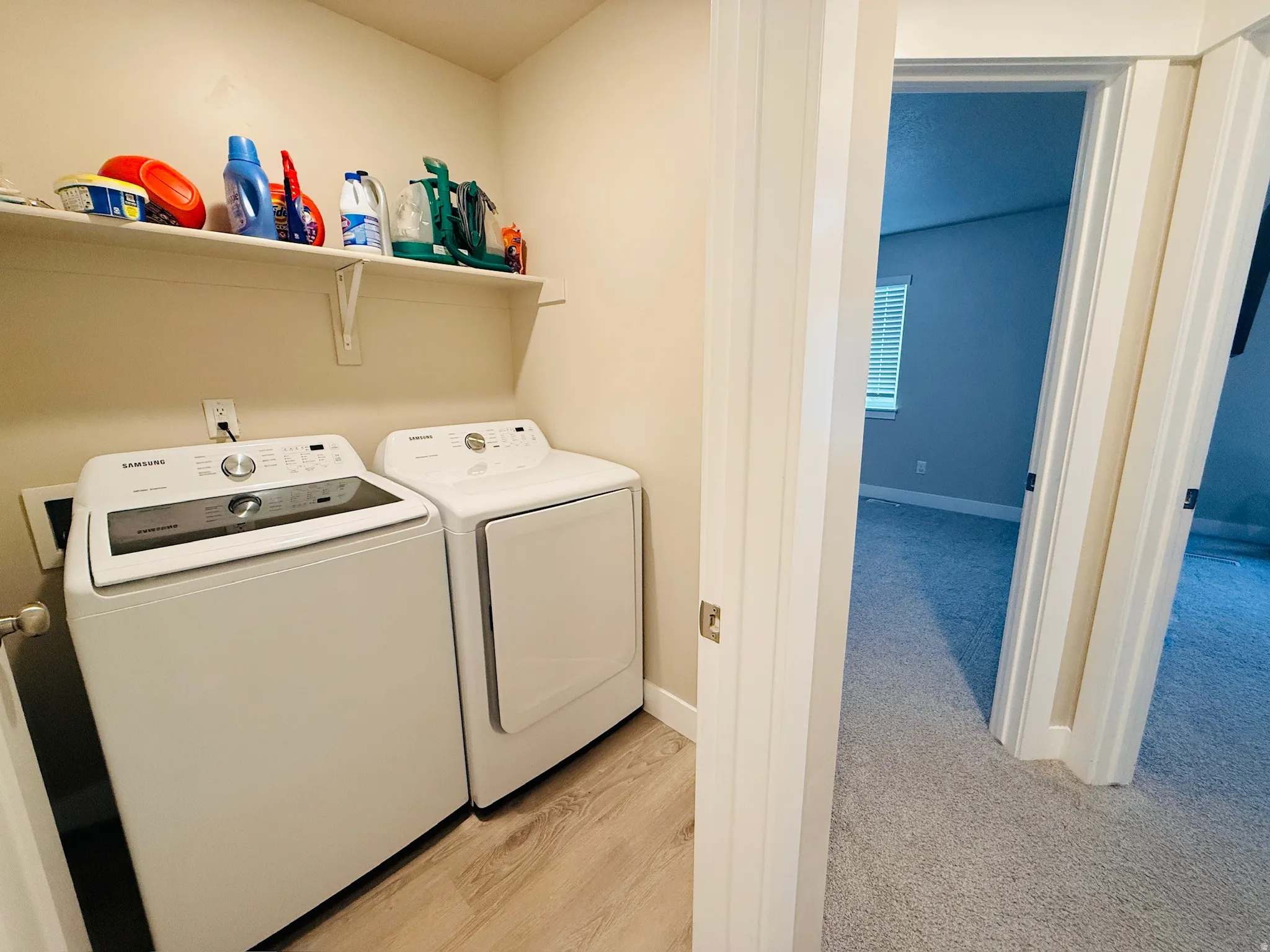 Laundry area with washer and clothes dryer and light wood-type flooring