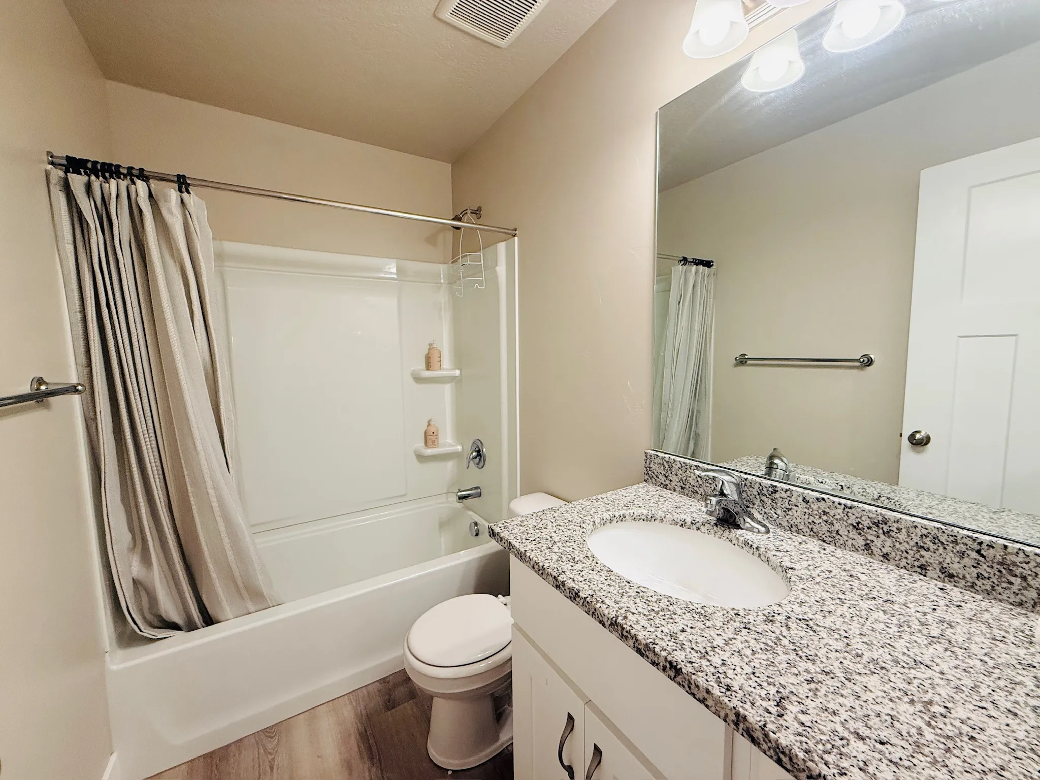 Bathroom featuring shower / tub combo with curtain, vanity, and dark wood-type flooring