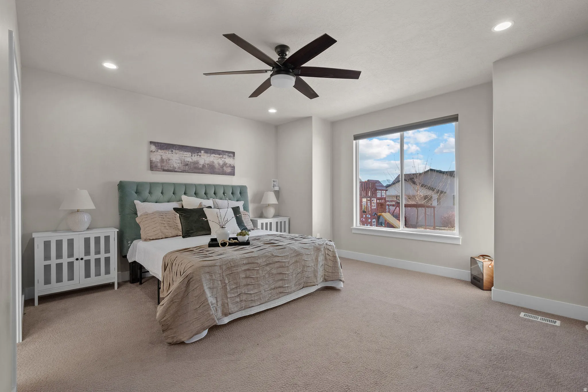 Carpeted bedroom with a ceiling fan and recessed lighting