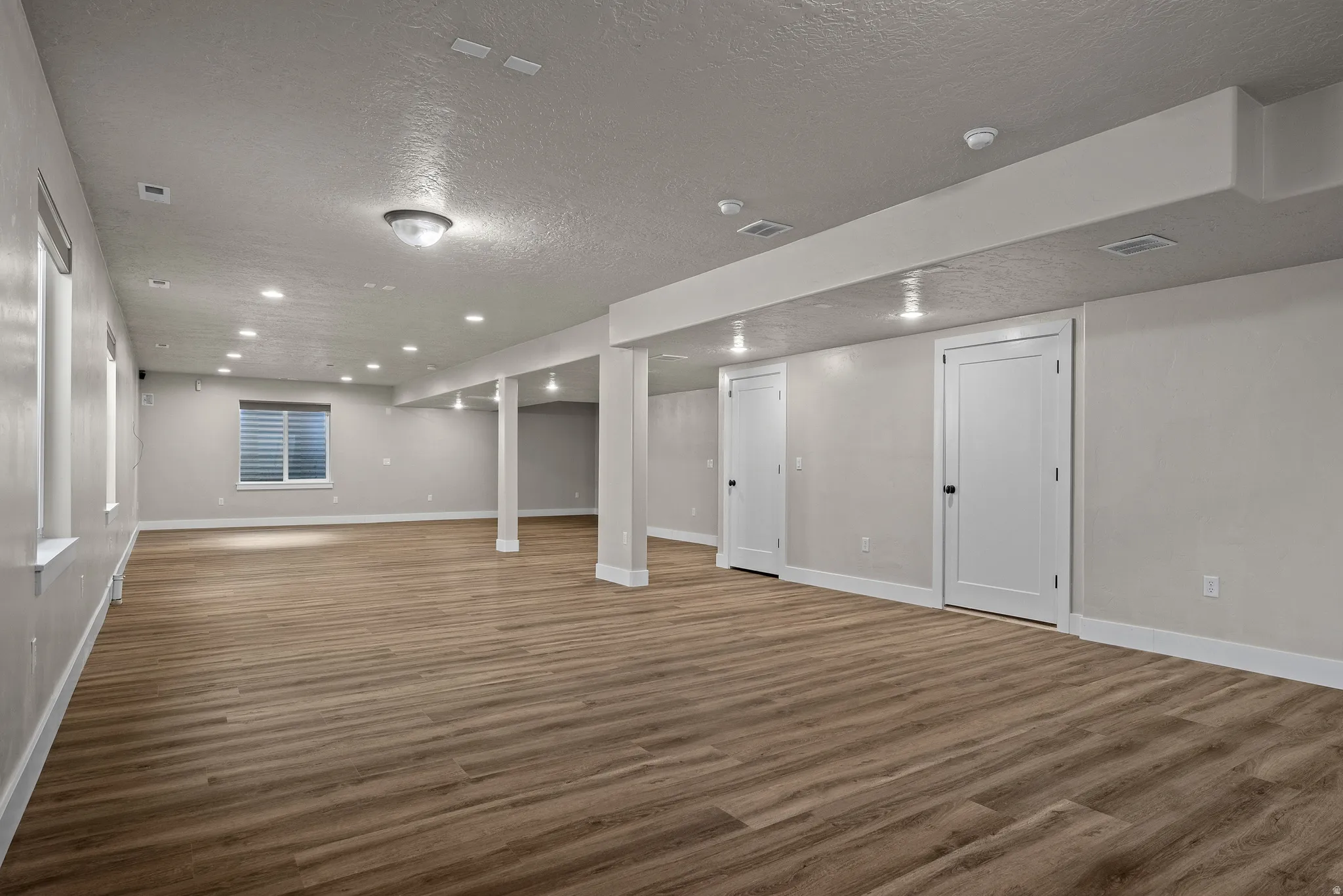 Finished basement featuring recessed lighting, a textured ceiling, and wood finished floors