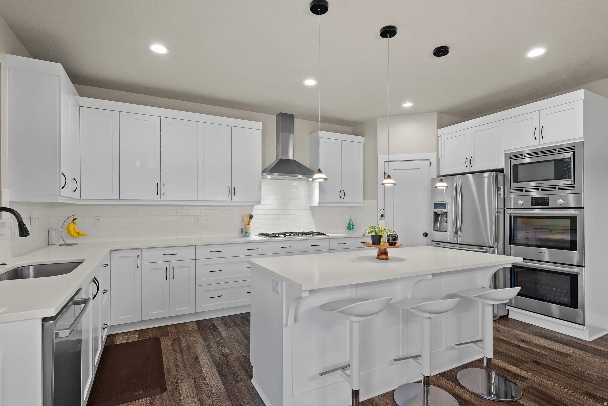 Kitchen featuring white cabinetry, a kitchen bar, appliances with stainless steel finishes, hanging light fixtures, and a center island