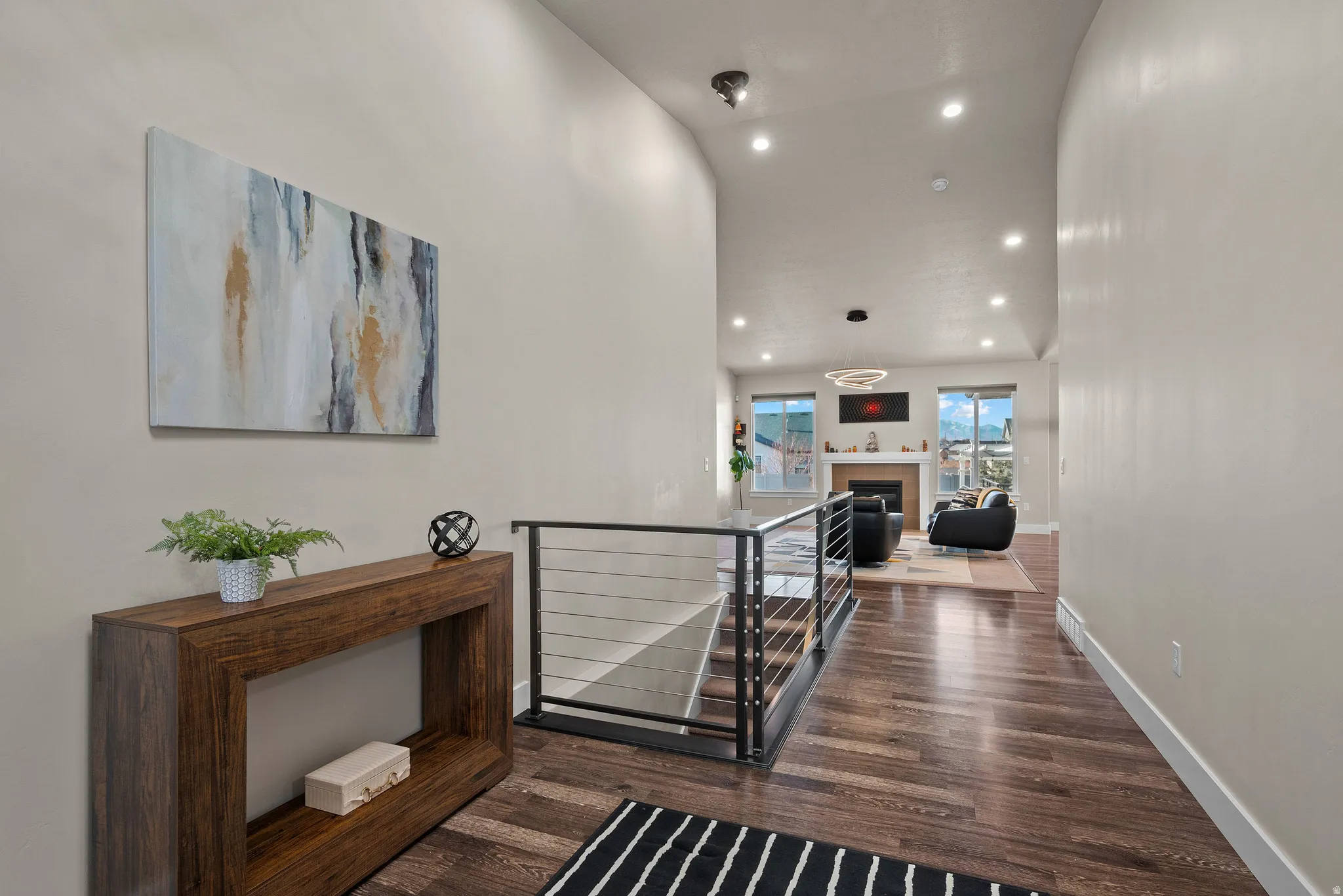Corridor with an upstairs landing, recessed lighting, dark wood-style flooring, and a high ceiling